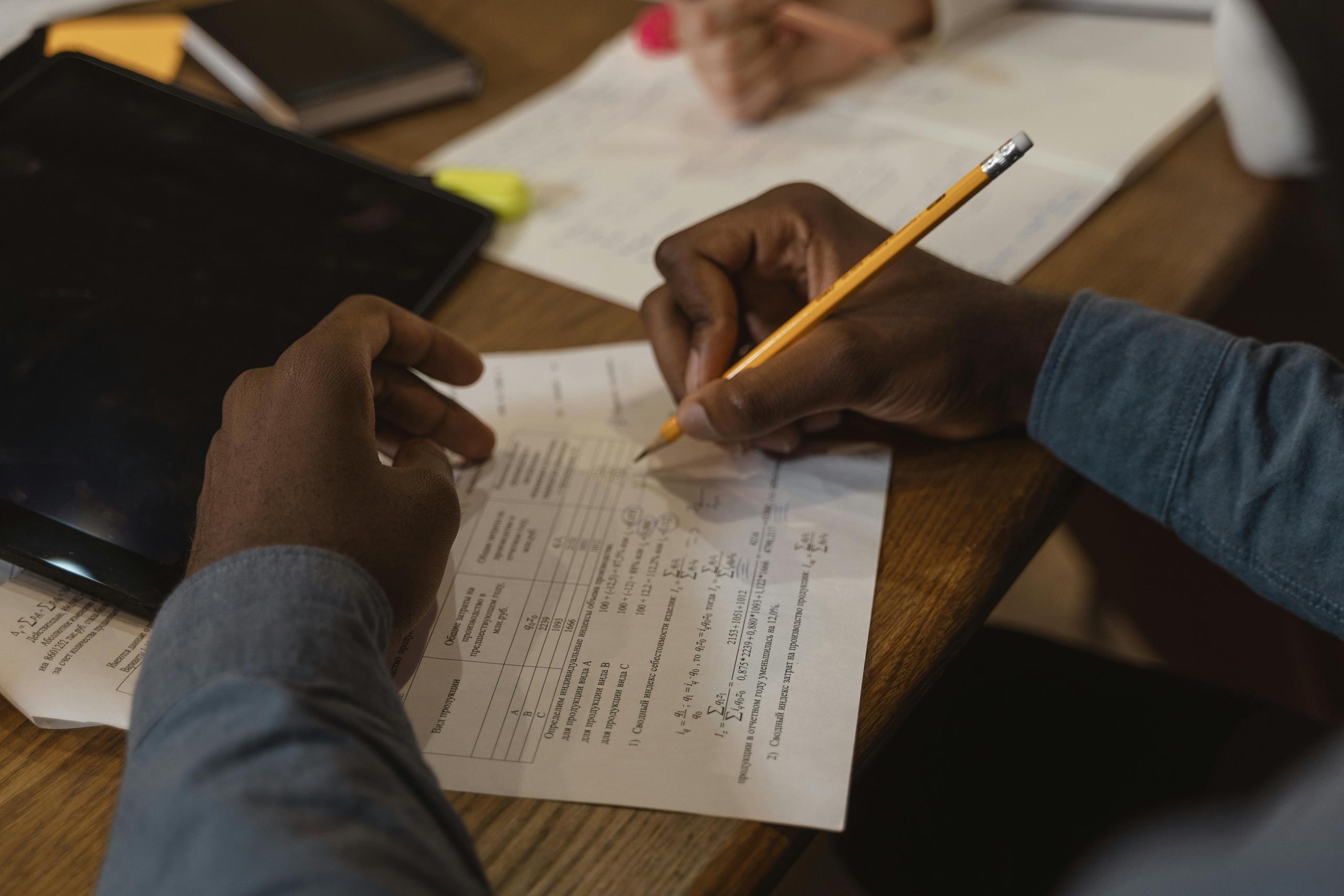 manos resolviendo unos ejercicios de matemáticas con formulas