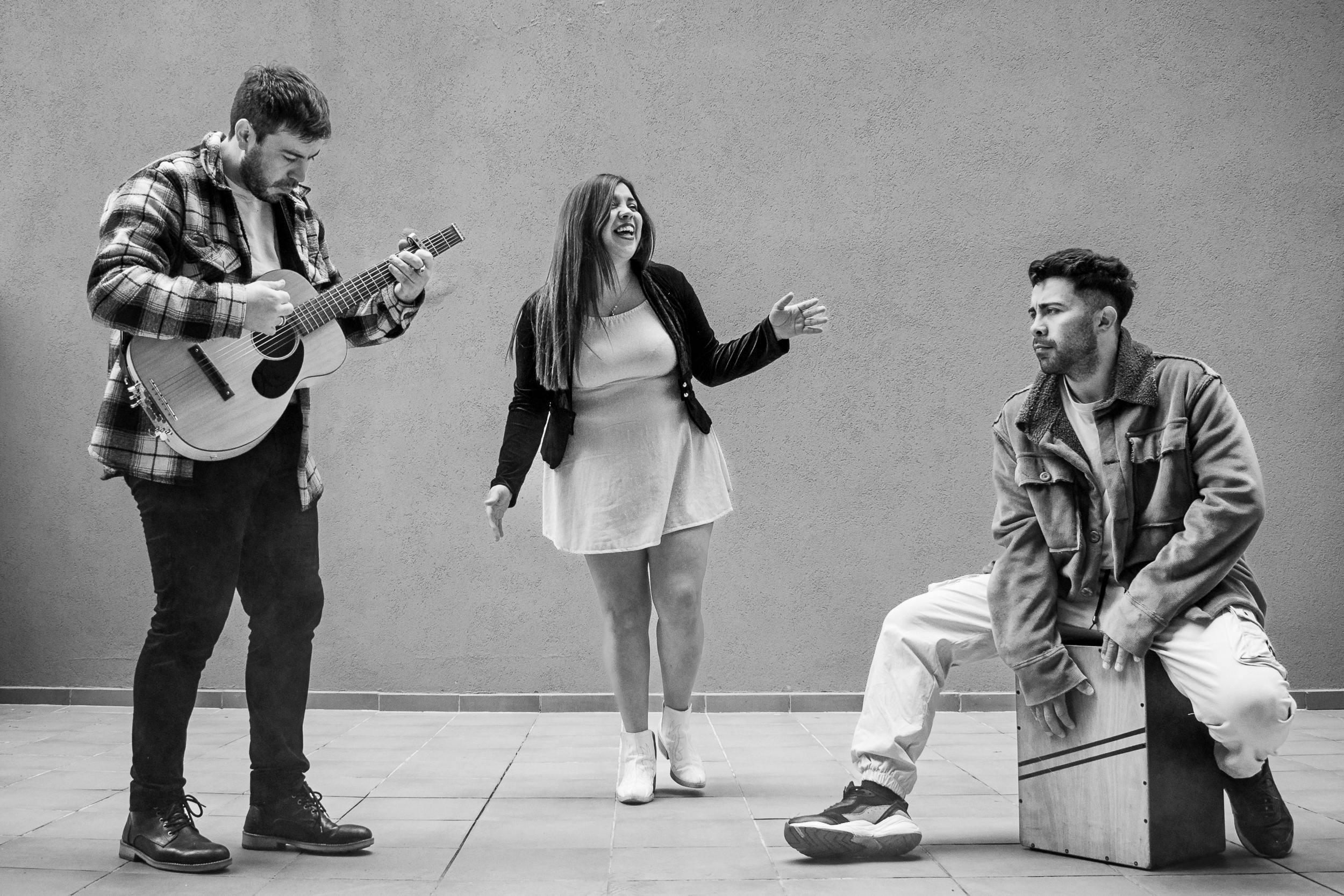 tres chicos riendo y tocando el cajón y la guitarra