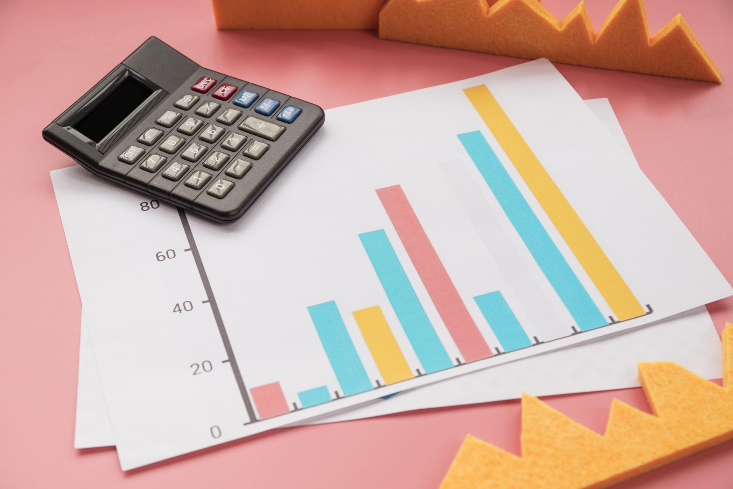 calculadora y reportes financieros sobre un fondo rosado