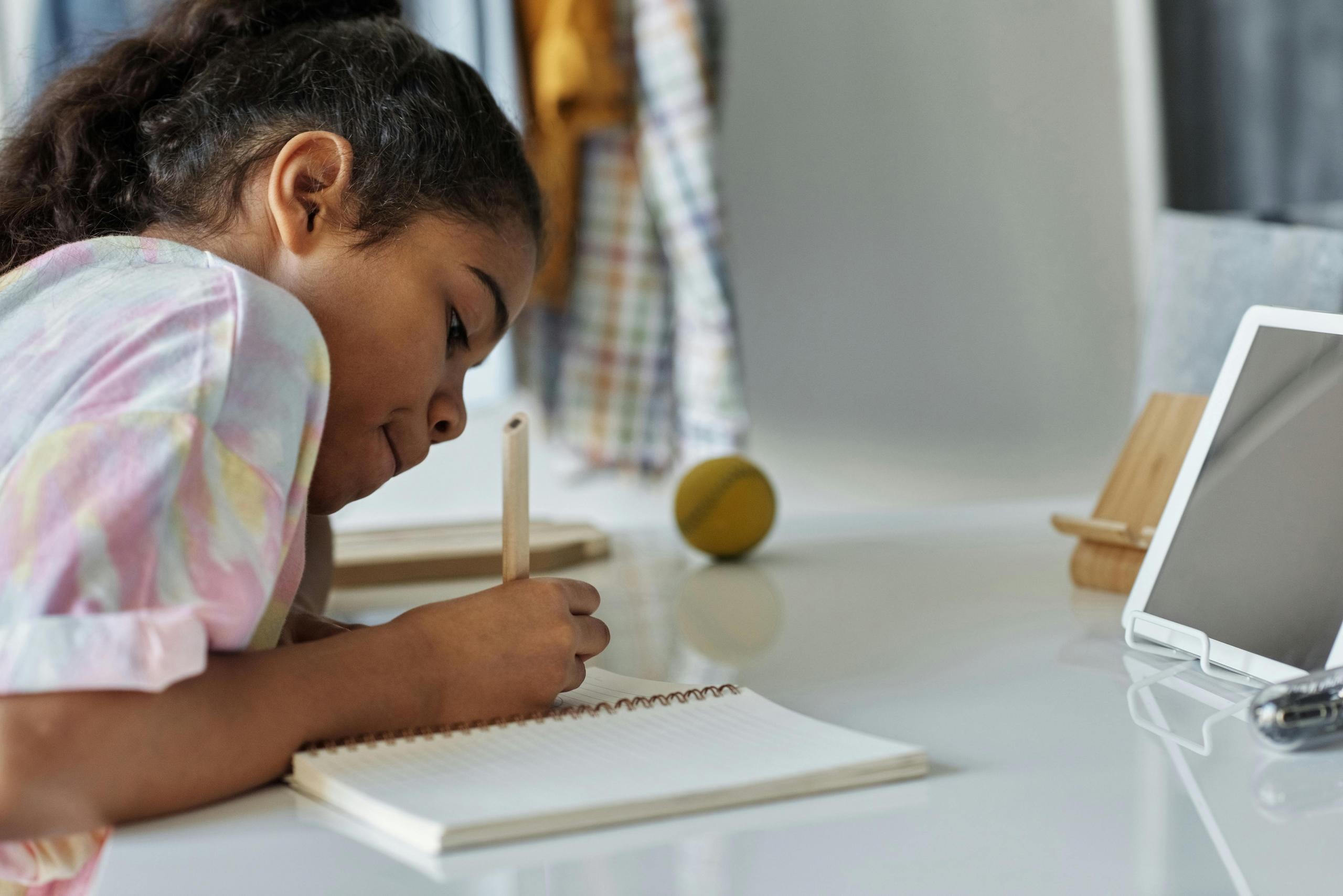 niña estudiando con un cuaderno y ipad al frente