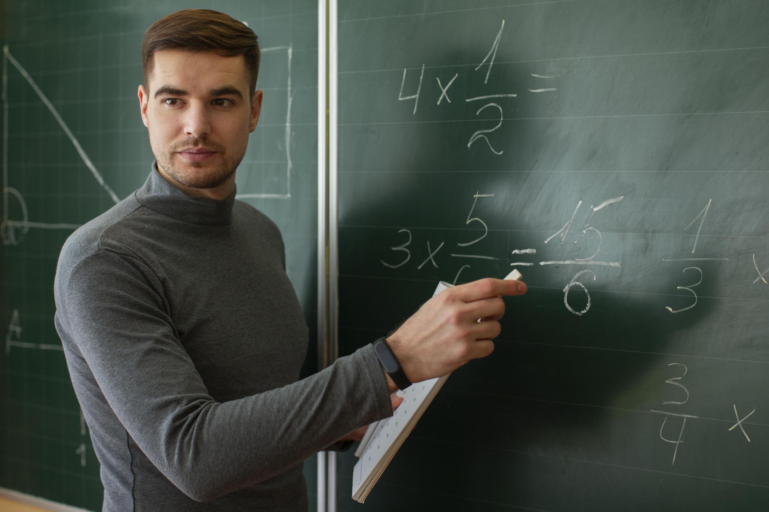 profesor escribiendo con tiza en una pizarra verde