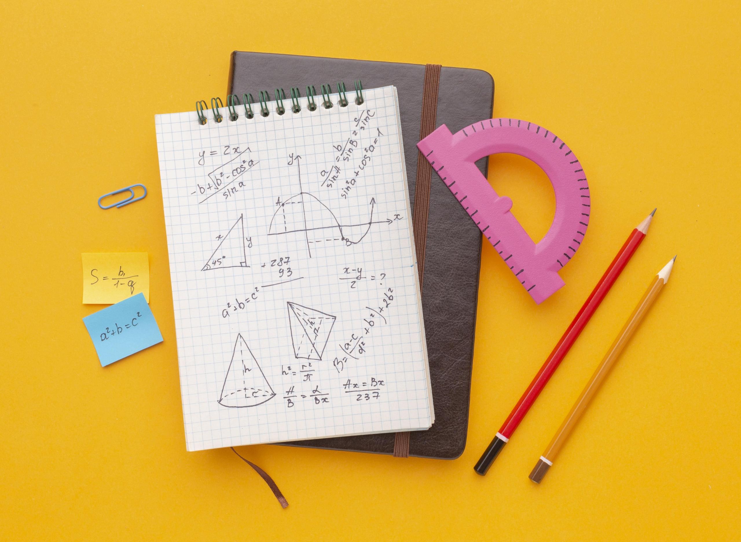 cuaderno con anotaciones matemáticas y post its alrededor con fórmulas en un fondo amarillo