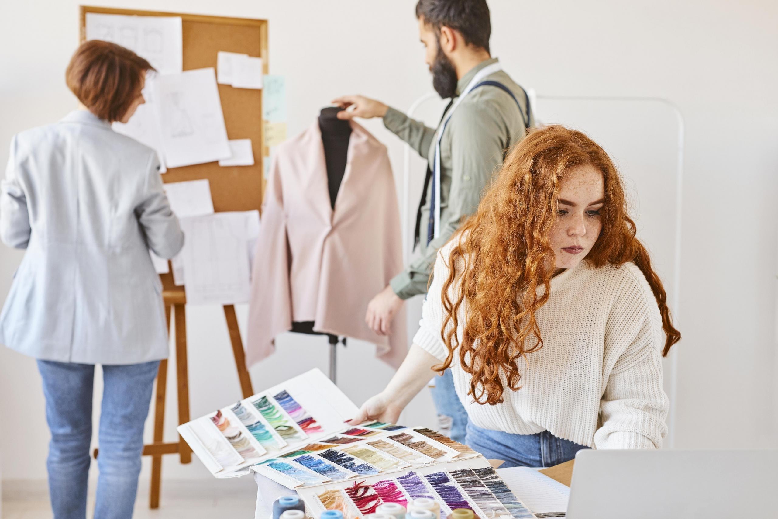 grupo de chicos trabajando en un diseño con bocetos, retazos y sastre