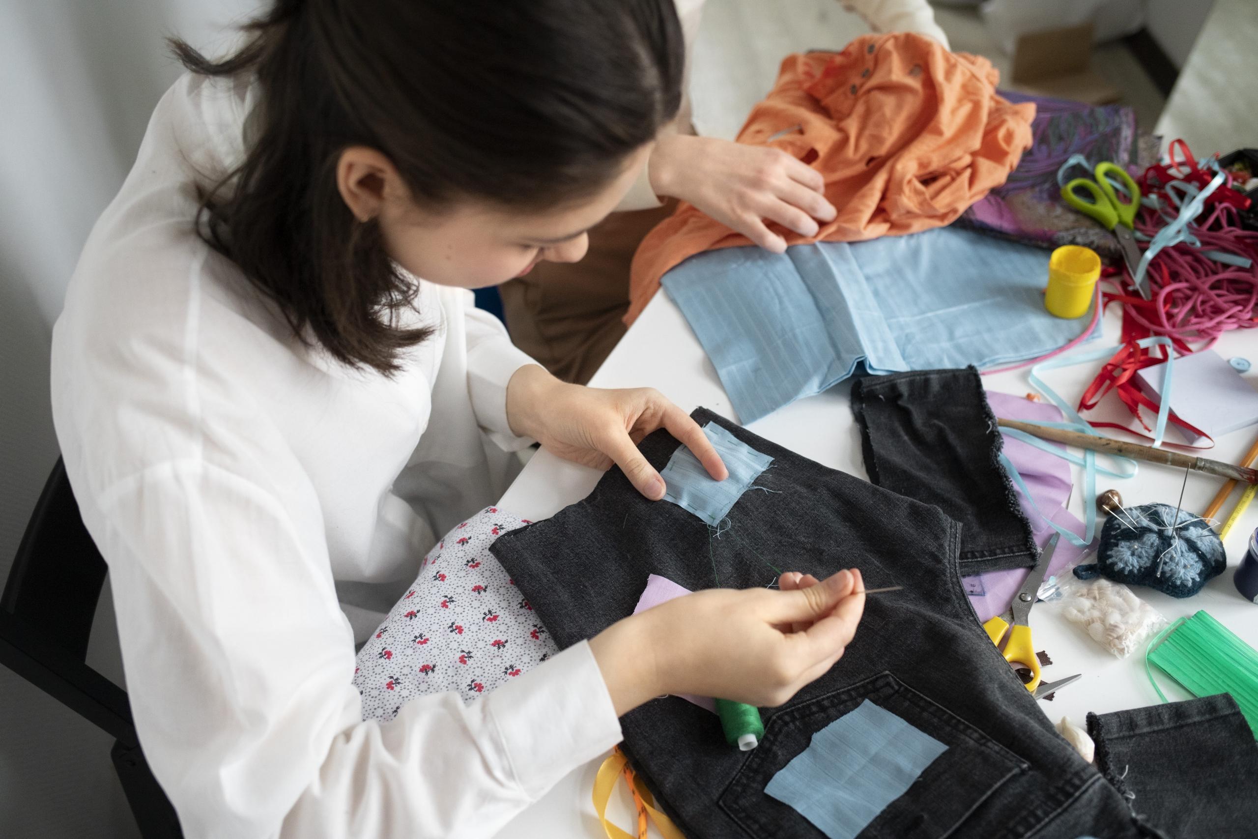vista cenital de mujer remendando un pantalón con parche