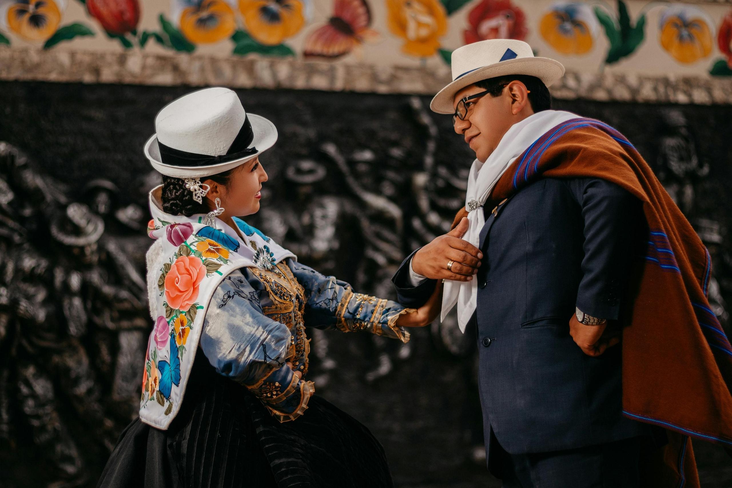 pareja vestida con traje típico de una danza peruana, mirándose frente a frente