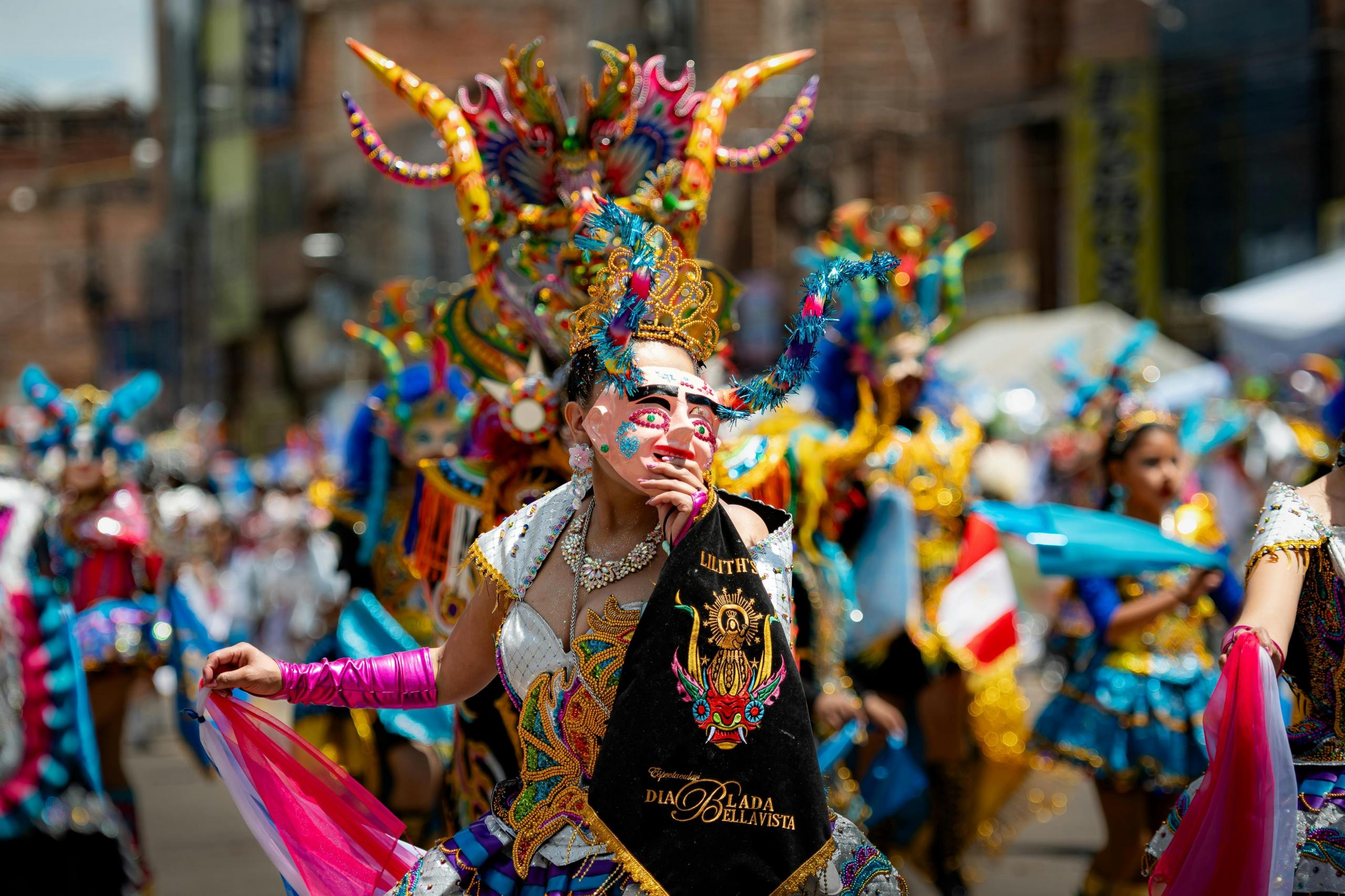 bailarina de la diablada sosteniendo una mascara en mano que tapa su rostro