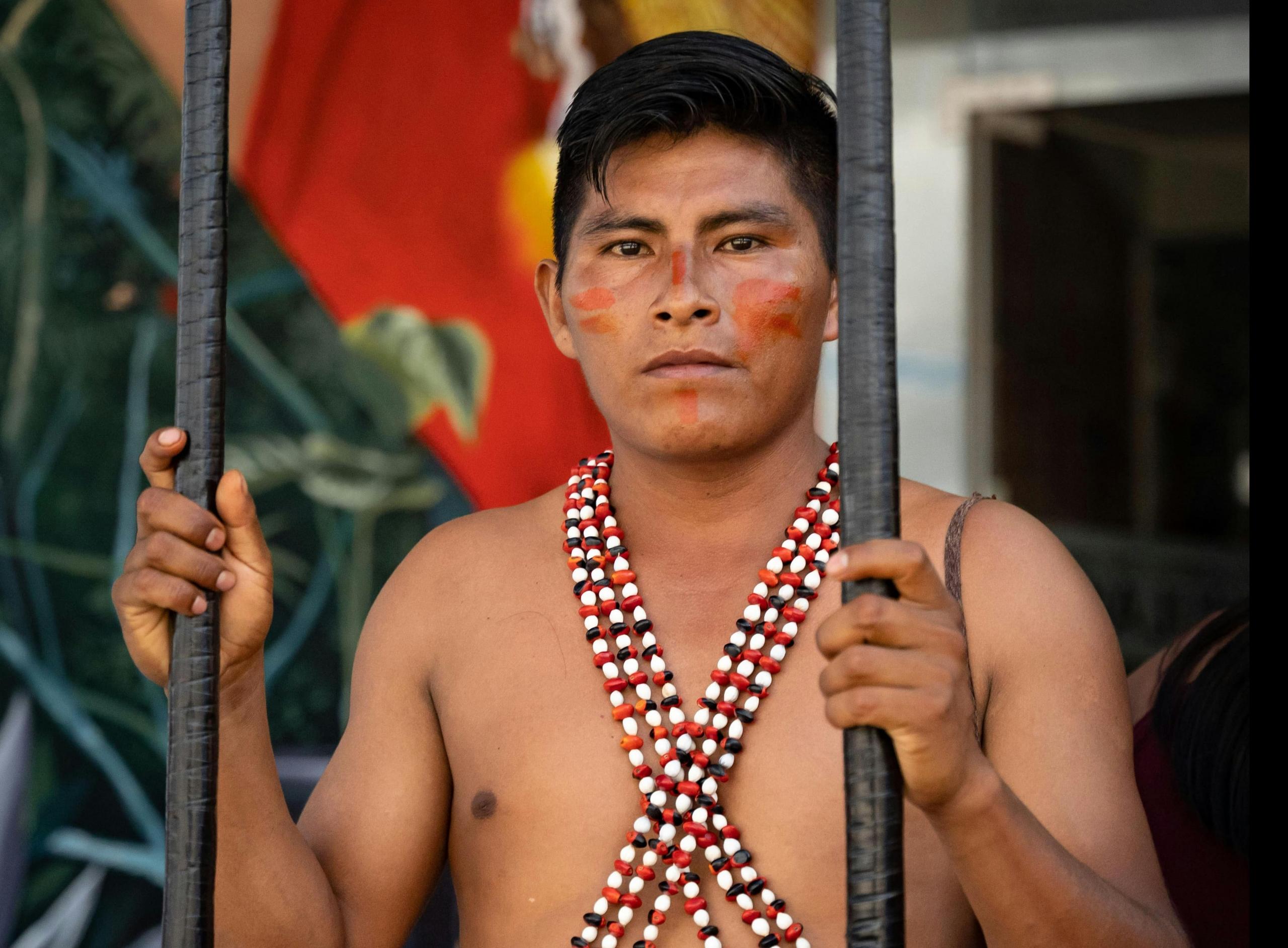 hombre shipibo sosteniendo unos bastones y mirando a la cámara