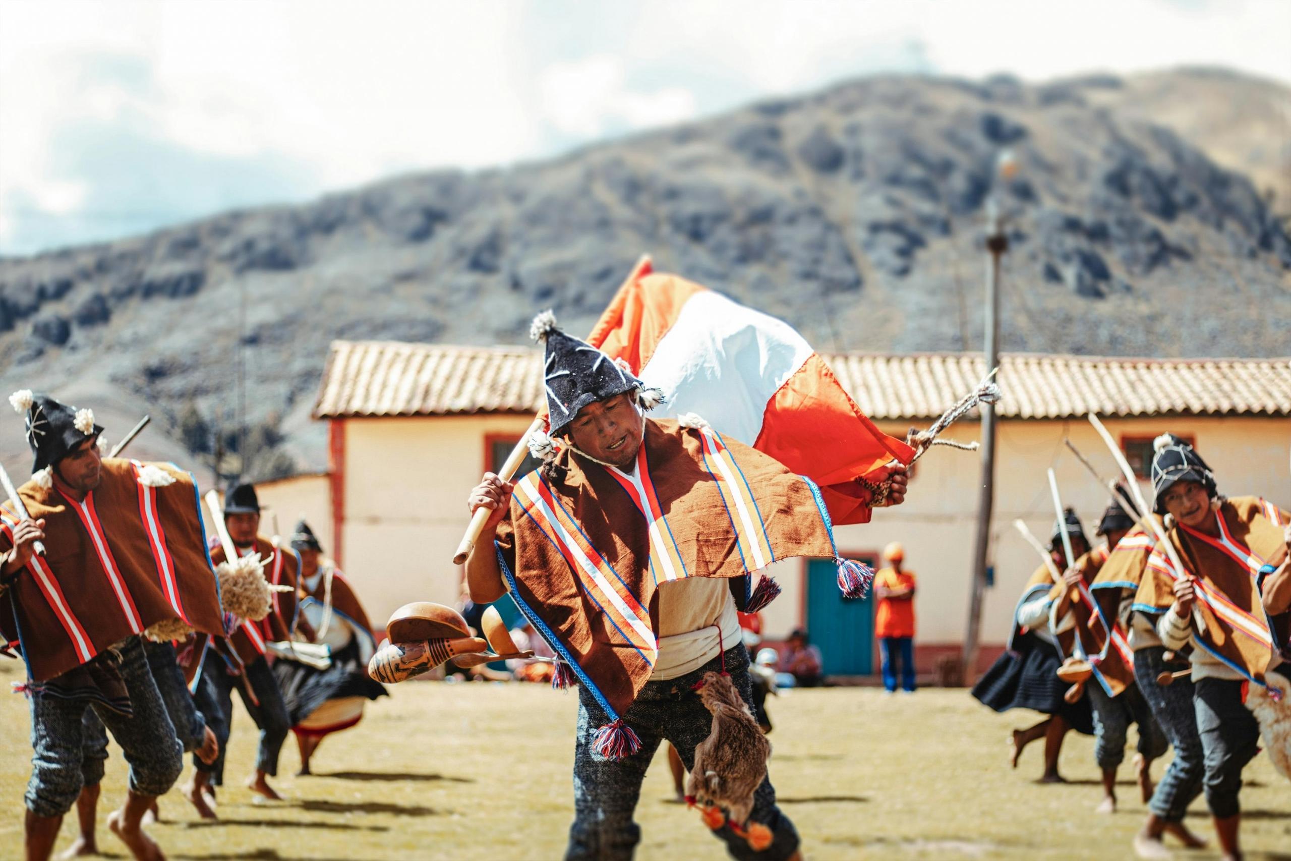 bailarin en medio de su coreografia sosteniendo una bandera del Perú en un campo