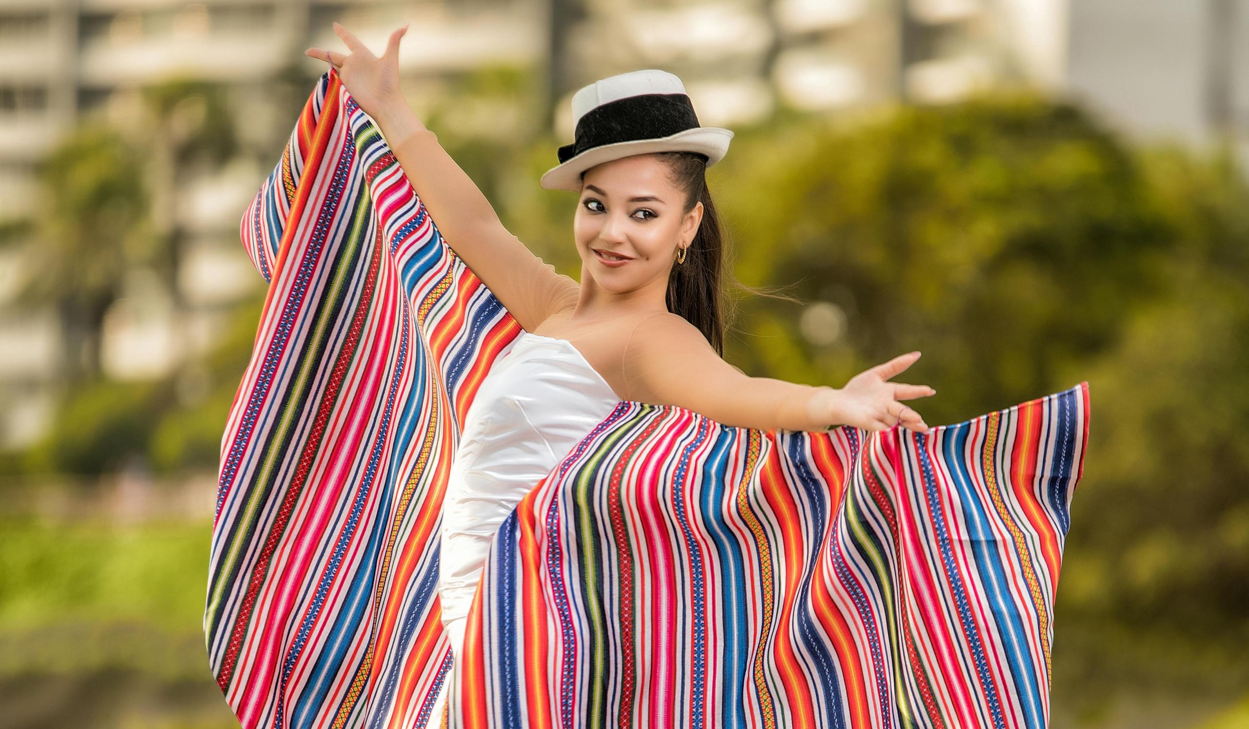 chica posando a la cámara y sosteniendo en sus brazos extendidos telares peruanos con diseño tradicional