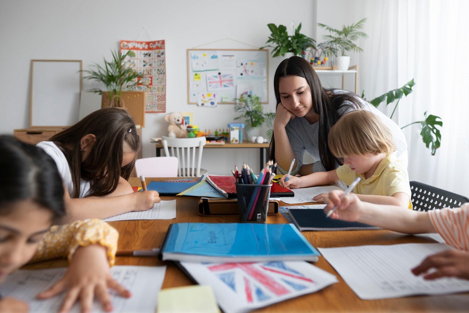 cuatro niños haciendo su tarea de inglés junto a la profesor observando lo que hacen