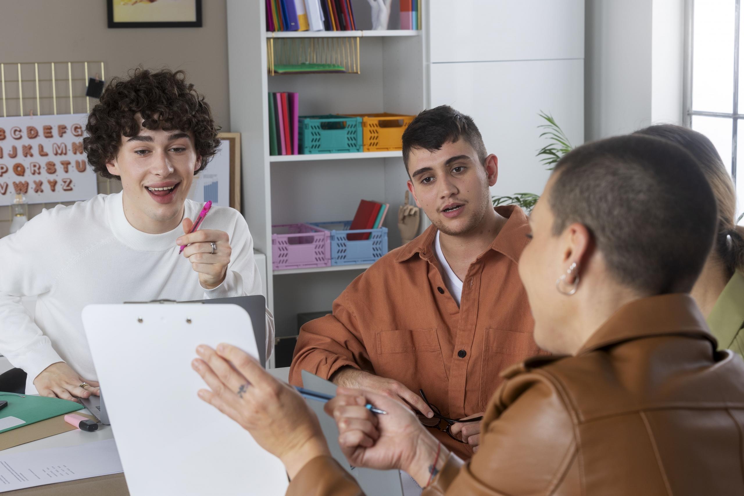 chica mostrando una hoja a un grupo de chicos con los que estudia