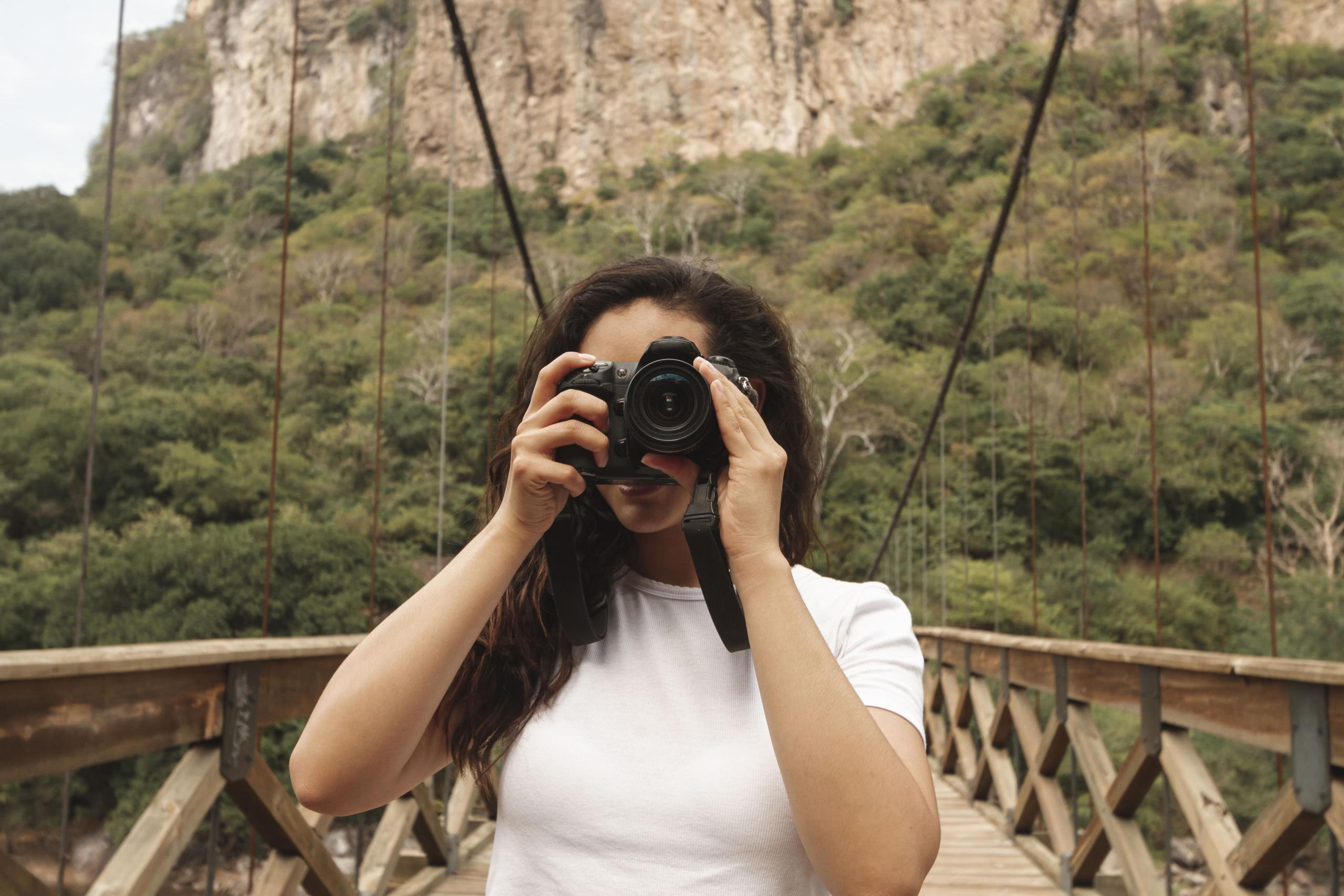 chica en un puente colgante con una cámara tapando su rostro
