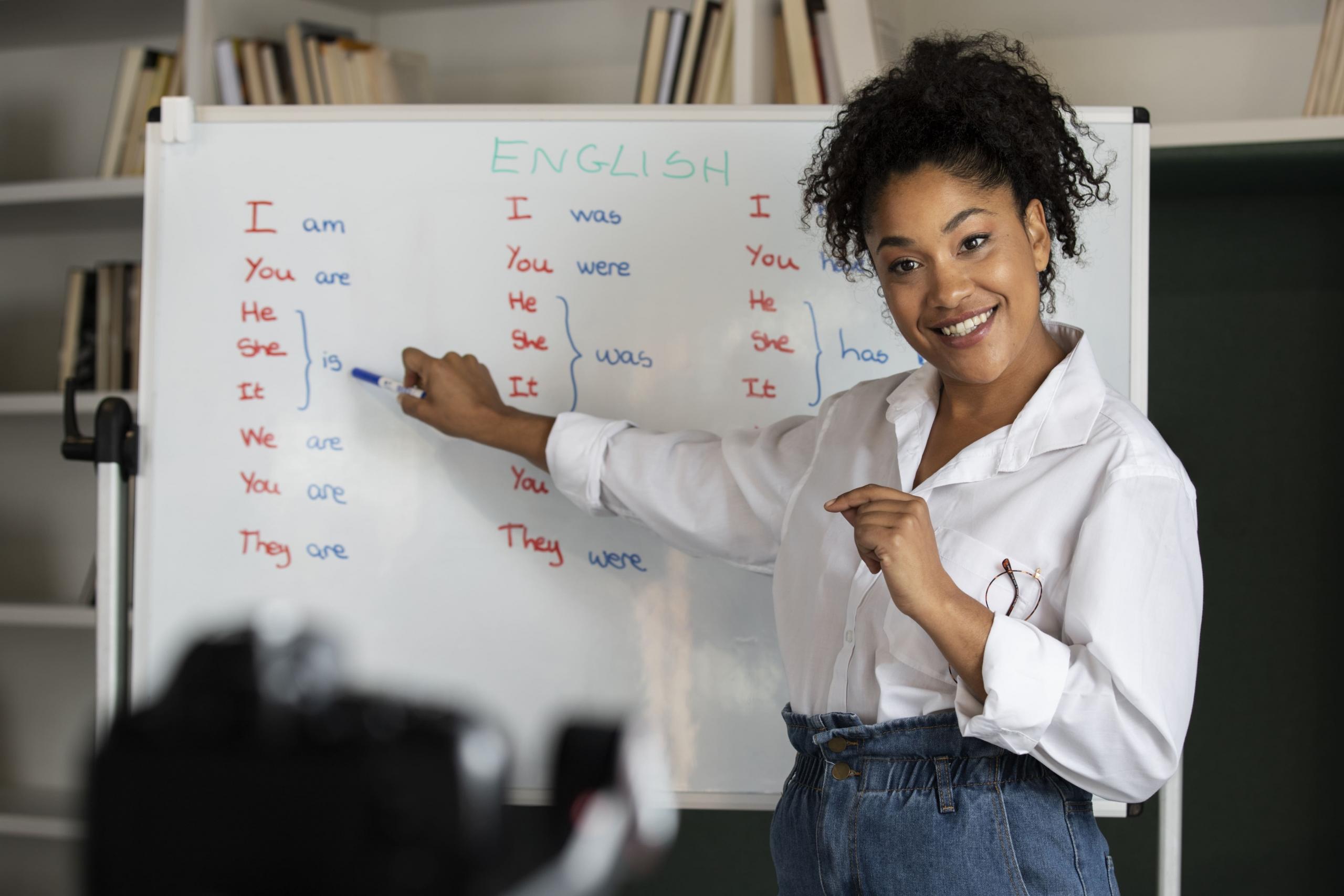 vista de maestra grabando su lección de inglés frente a una pizarra
