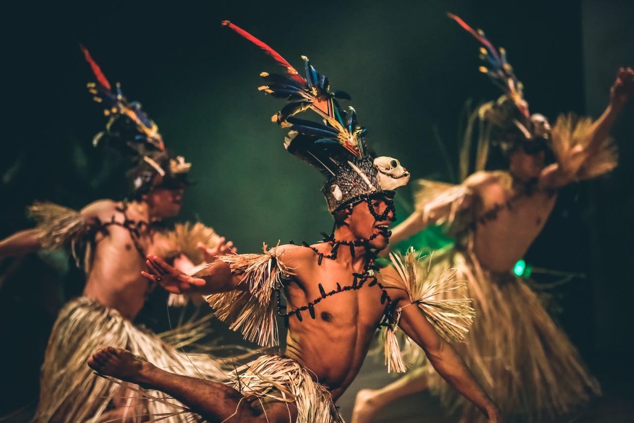 tres bailarines con trajes amazónico típicos en una presentación de escenario