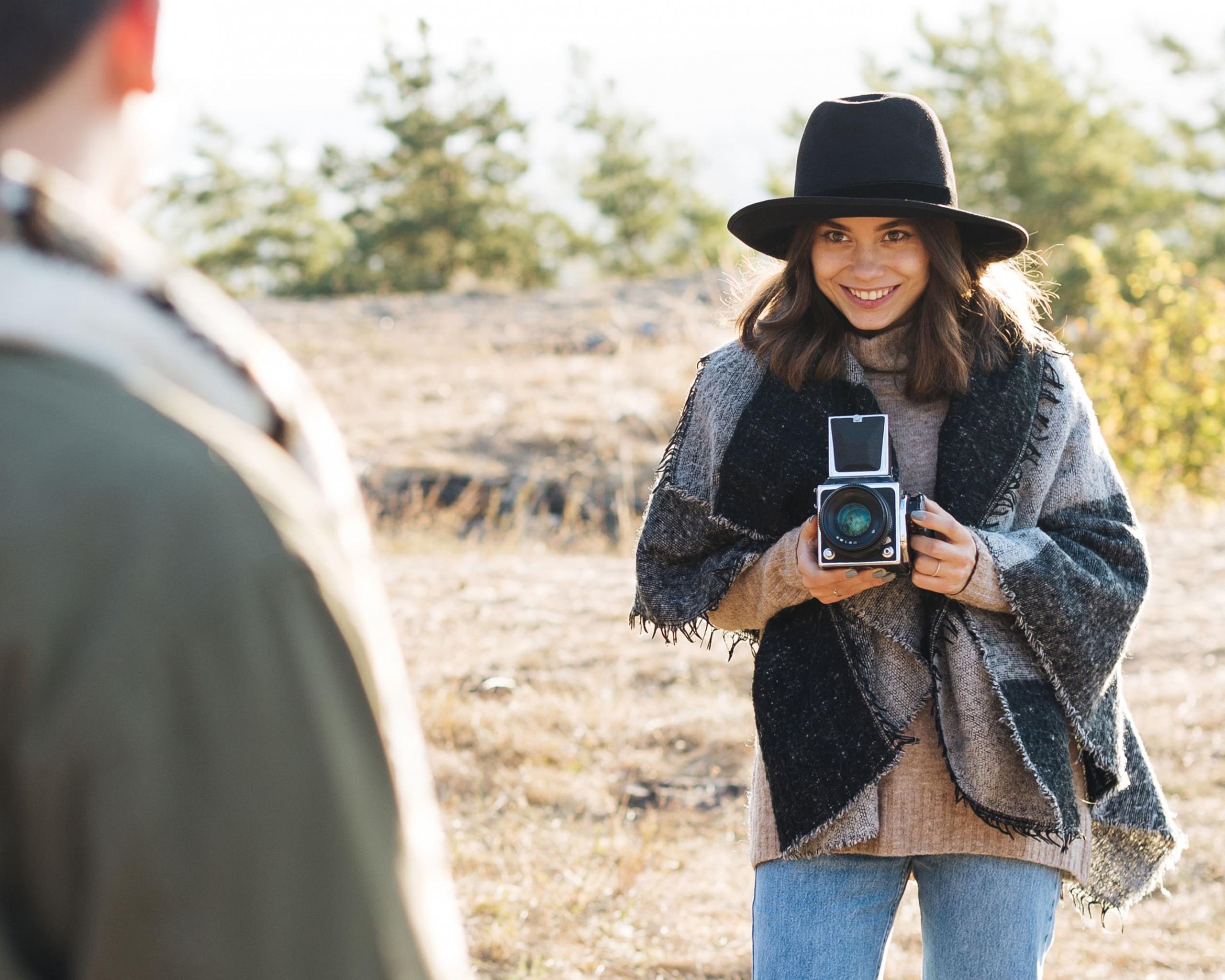 chica con poncho tomando una foto a un chico, con una cámara vintage