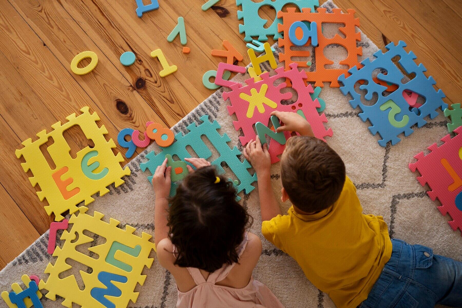 vista cenital de dos niños jugando con letras armables gigantes sobre el piso