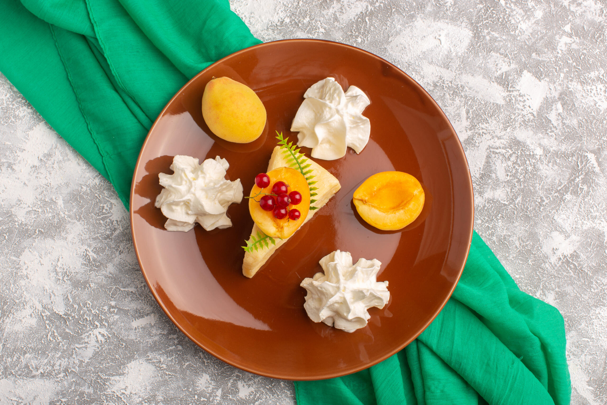vista cenital de una porción de cheescake decorado chantilly y rodajas de durazno en un plato