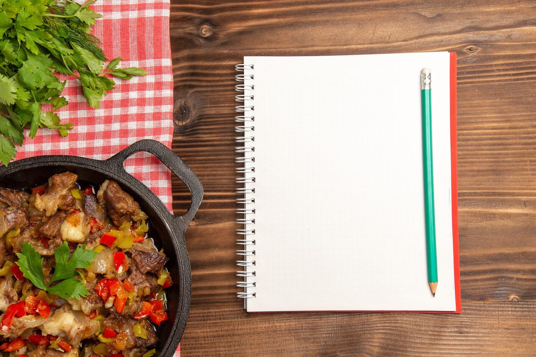 vista cenital de plato de comida junto a un cuaderno en blanco y lapiz