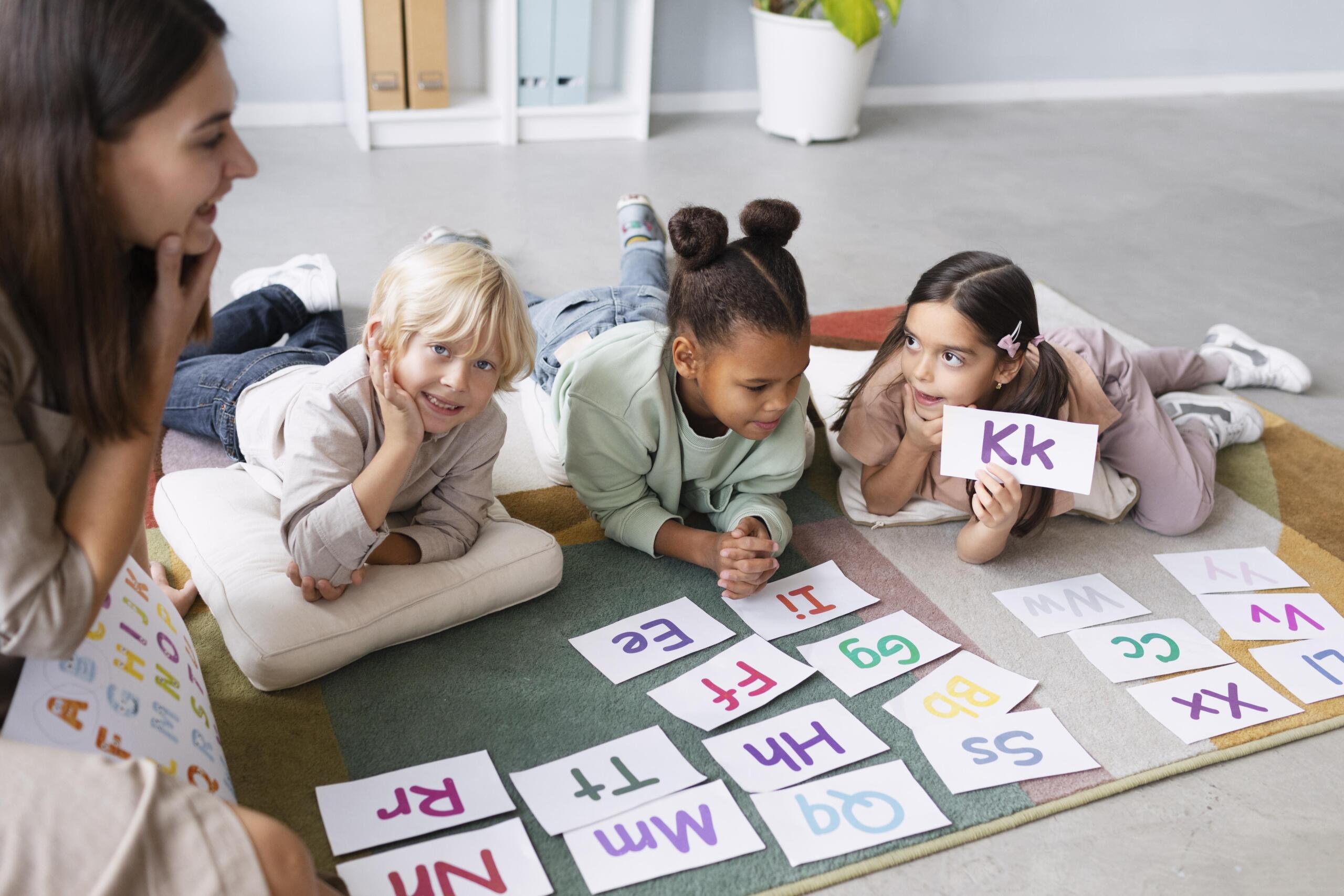 niños tendidos en el piso repasando la pronunciación de las letras con su maestra