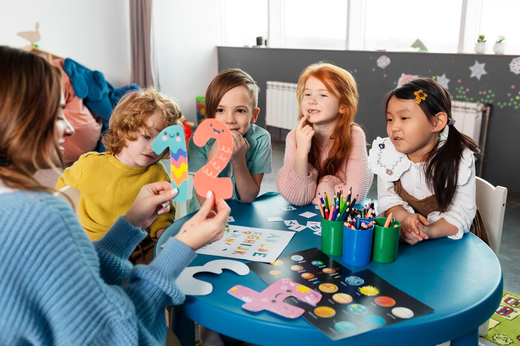 grupo de cuatro niños junto a la maestra mirando los números y letras que ella les muestra