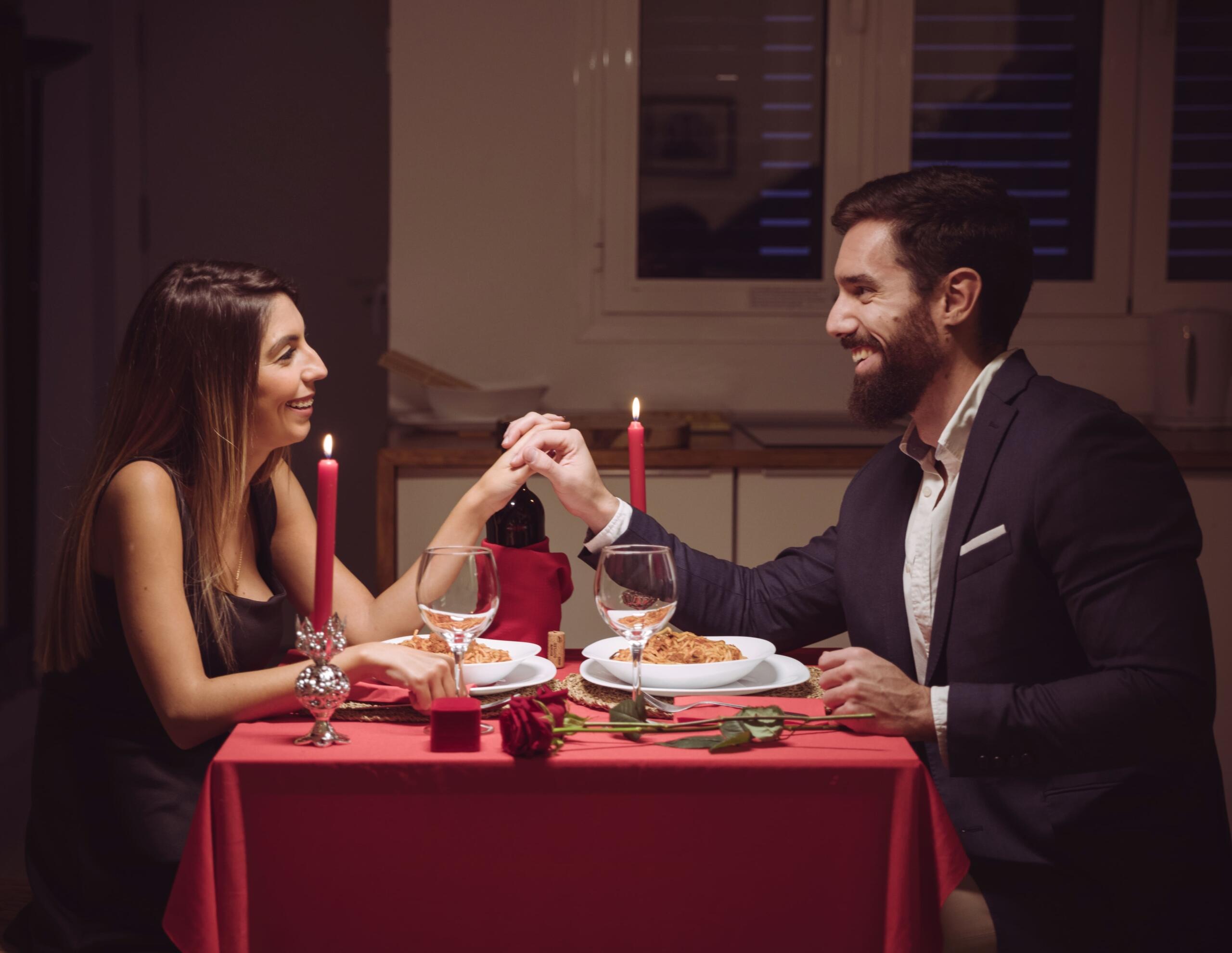 pareja en cena romántica mirandose sonrientes y tomándose de la mano