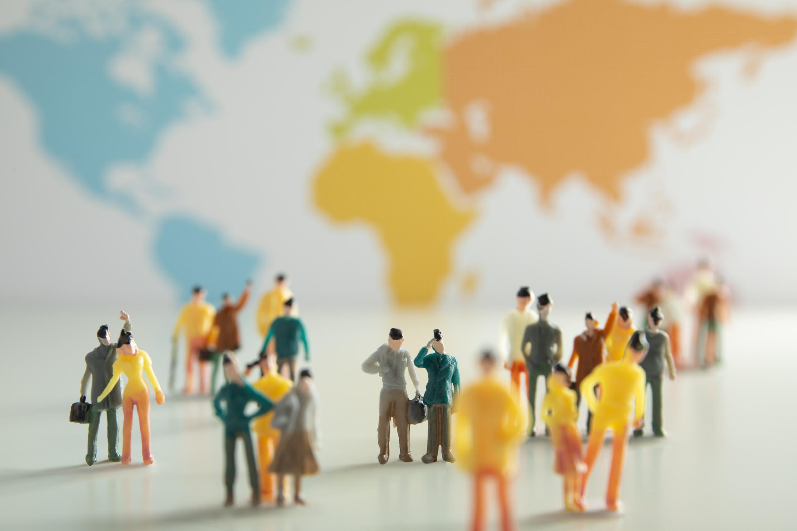 vista frontal de varios muñequitos de maqueta de colores con un fondo del mapa mundial desenfocado