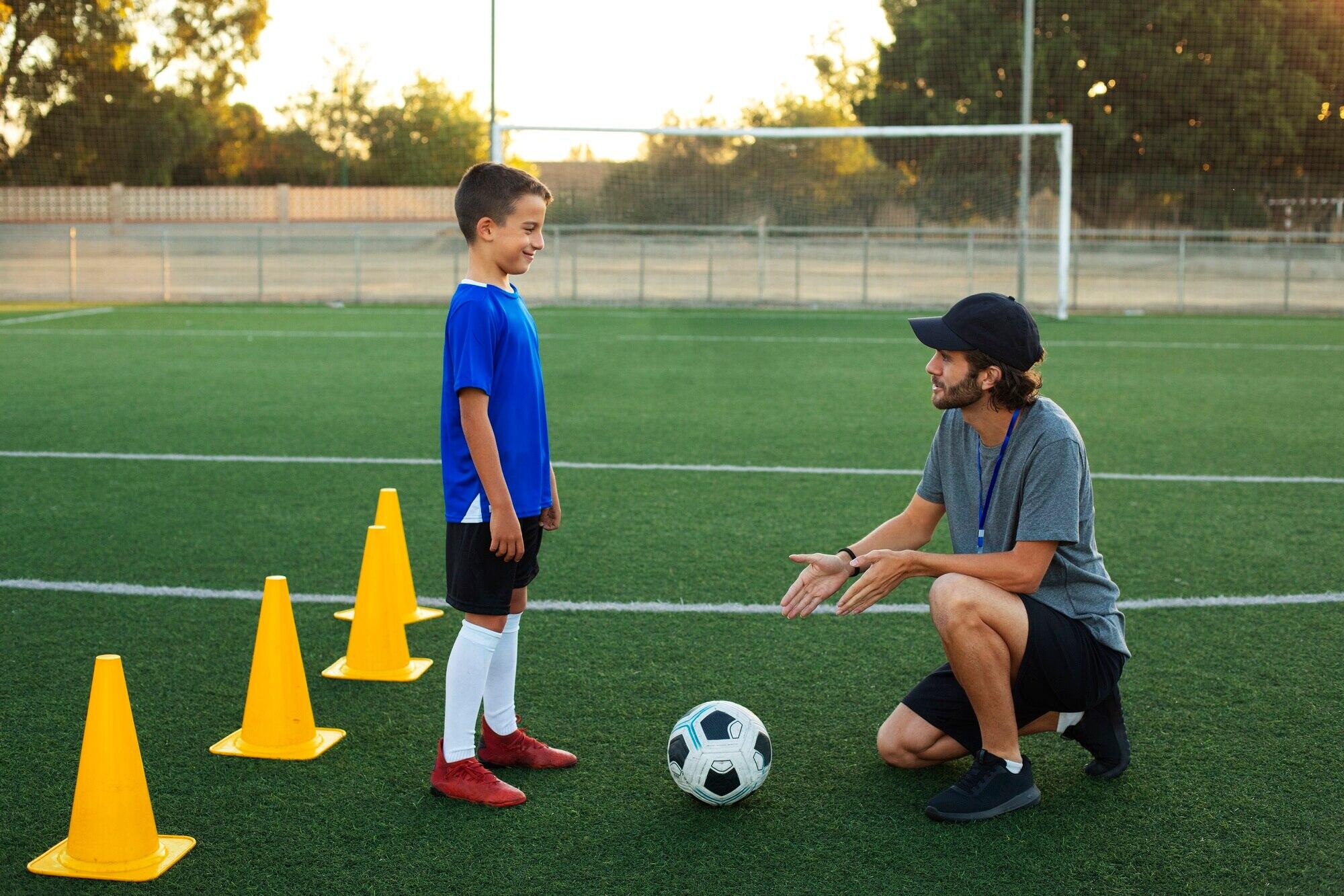 niño junto a su entrenador en la cancha