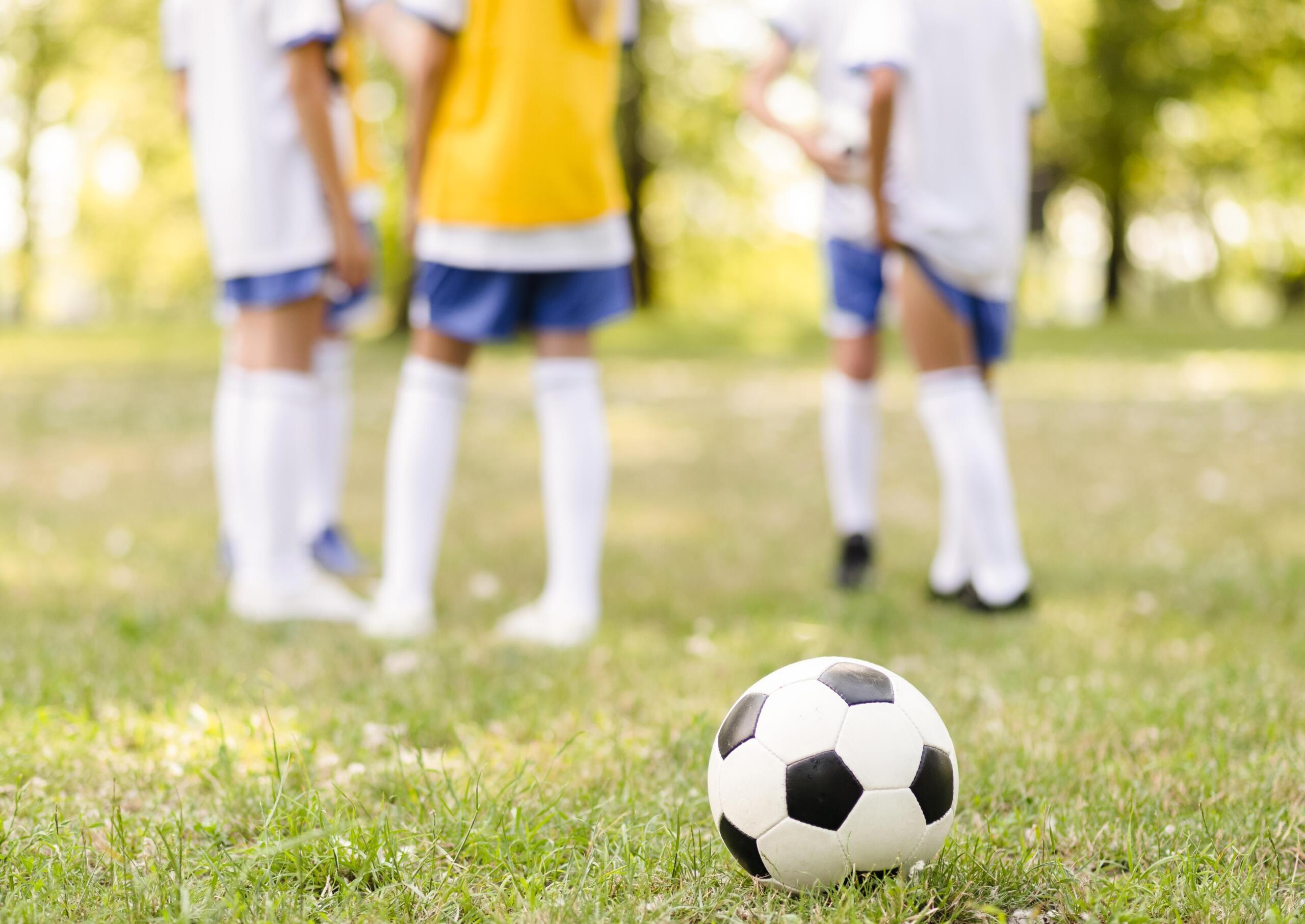 balón en primer plano y cuatro niños atrás en fondo desenfocado