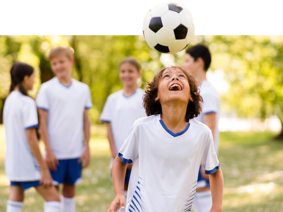niño cabeceando una pelota que está saliendo de la foto