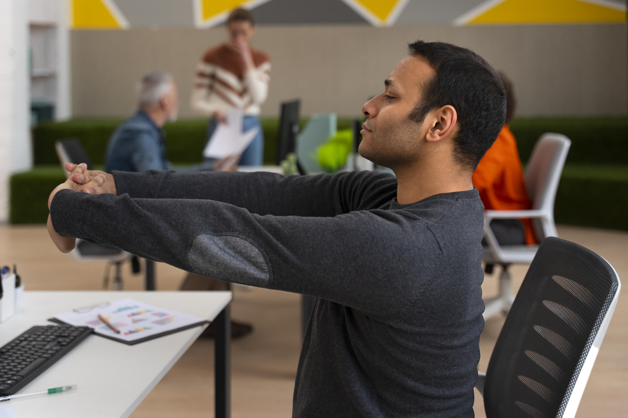 chico estirando los brazos con manos enlazadas frente a la computadora