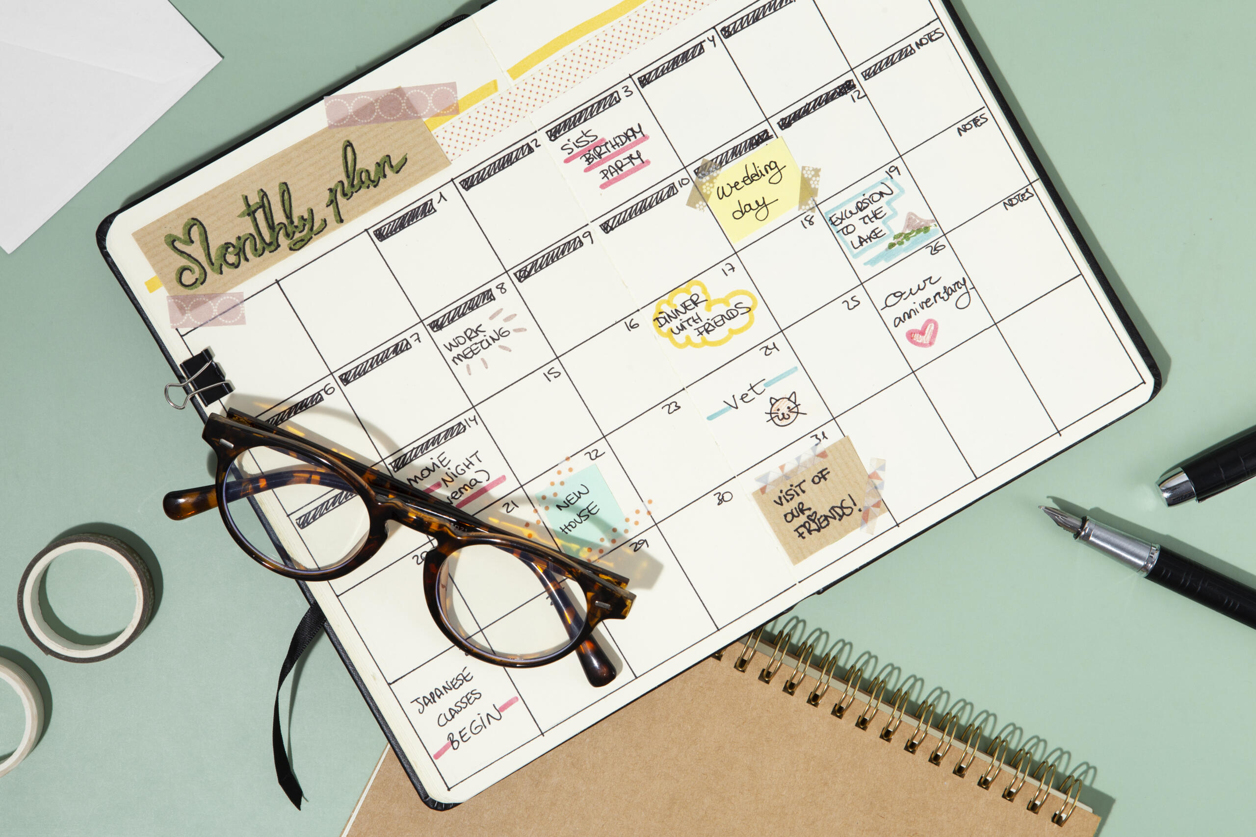 vista cenital de un calendario tipo scrapbook lleno de actividades junto a lentes lapices y cintas alrededor