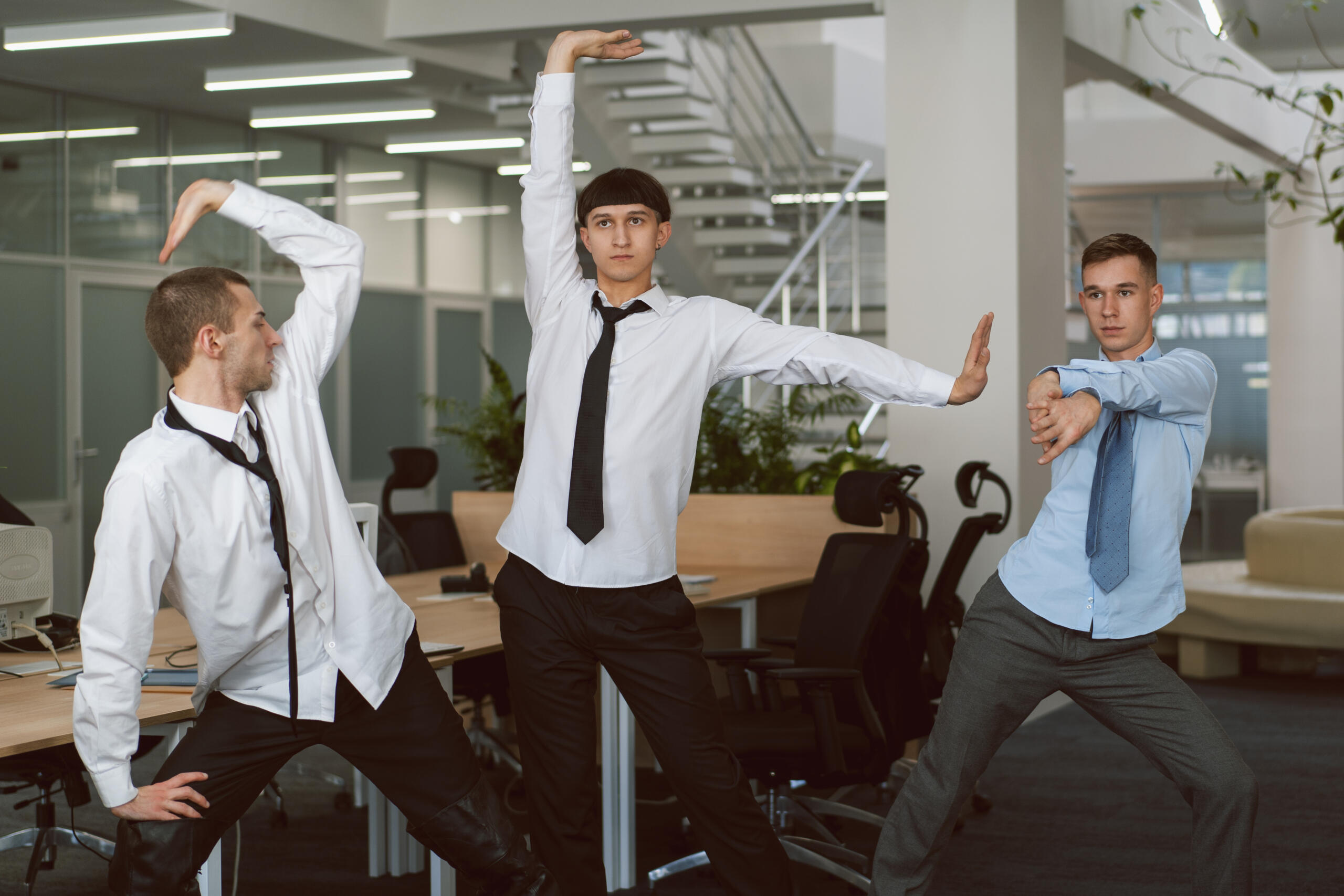 tres chicos haciendo estiramientos divertidos juntos en la oficina