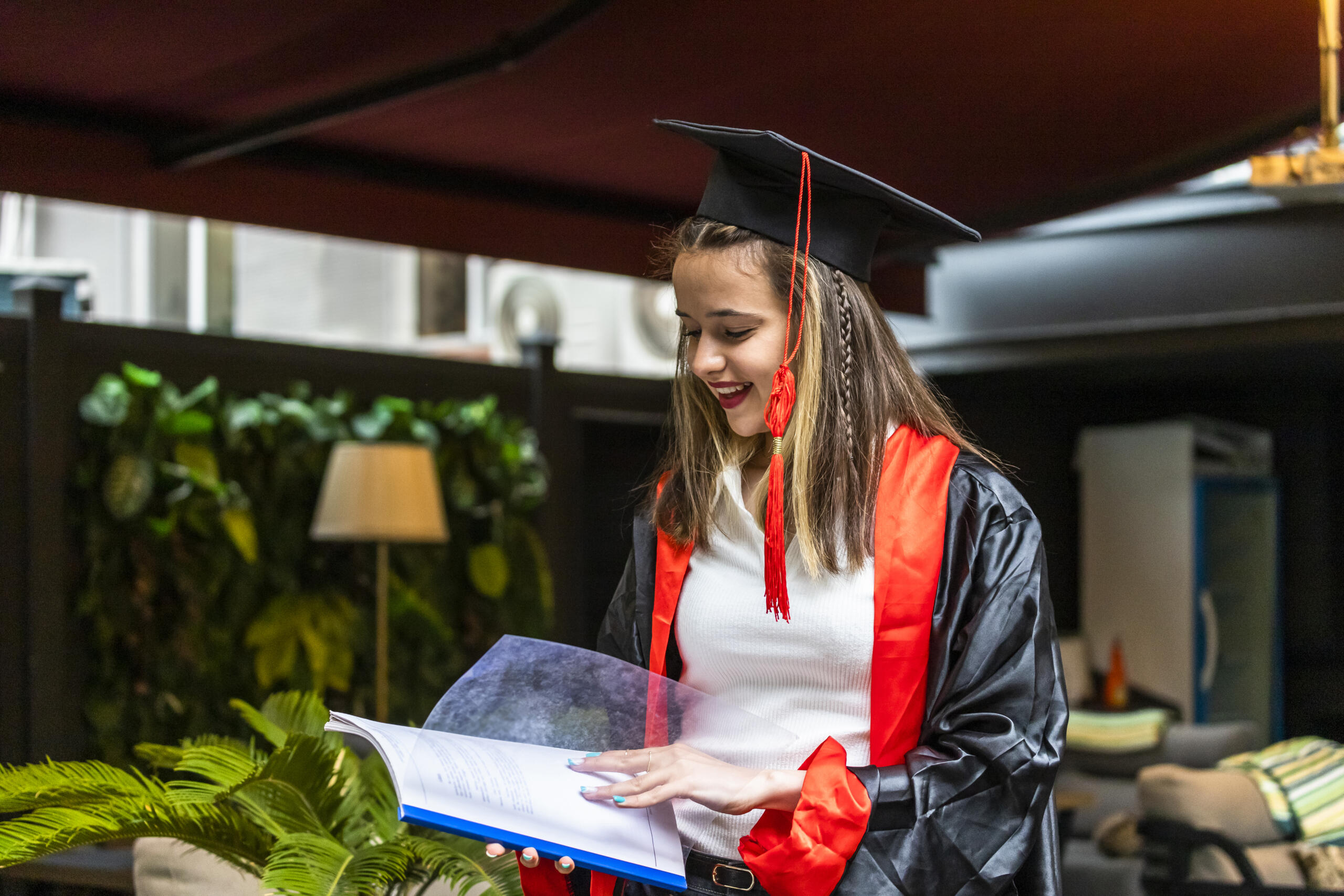 chica vestida con ropa de graduación revisando un libro