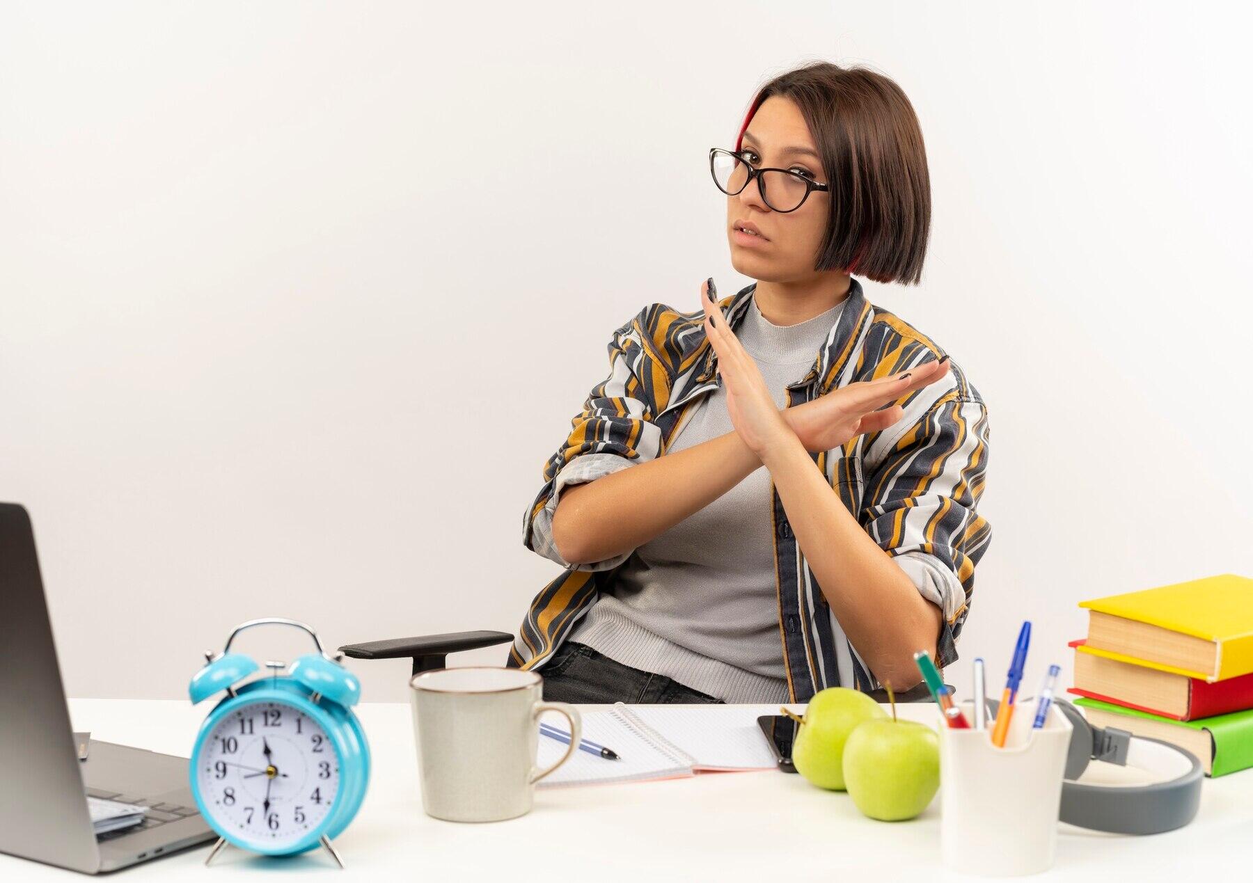 chica con rostro cansado y manos cruzadas en negativa a seguir estudiando en su escritorio