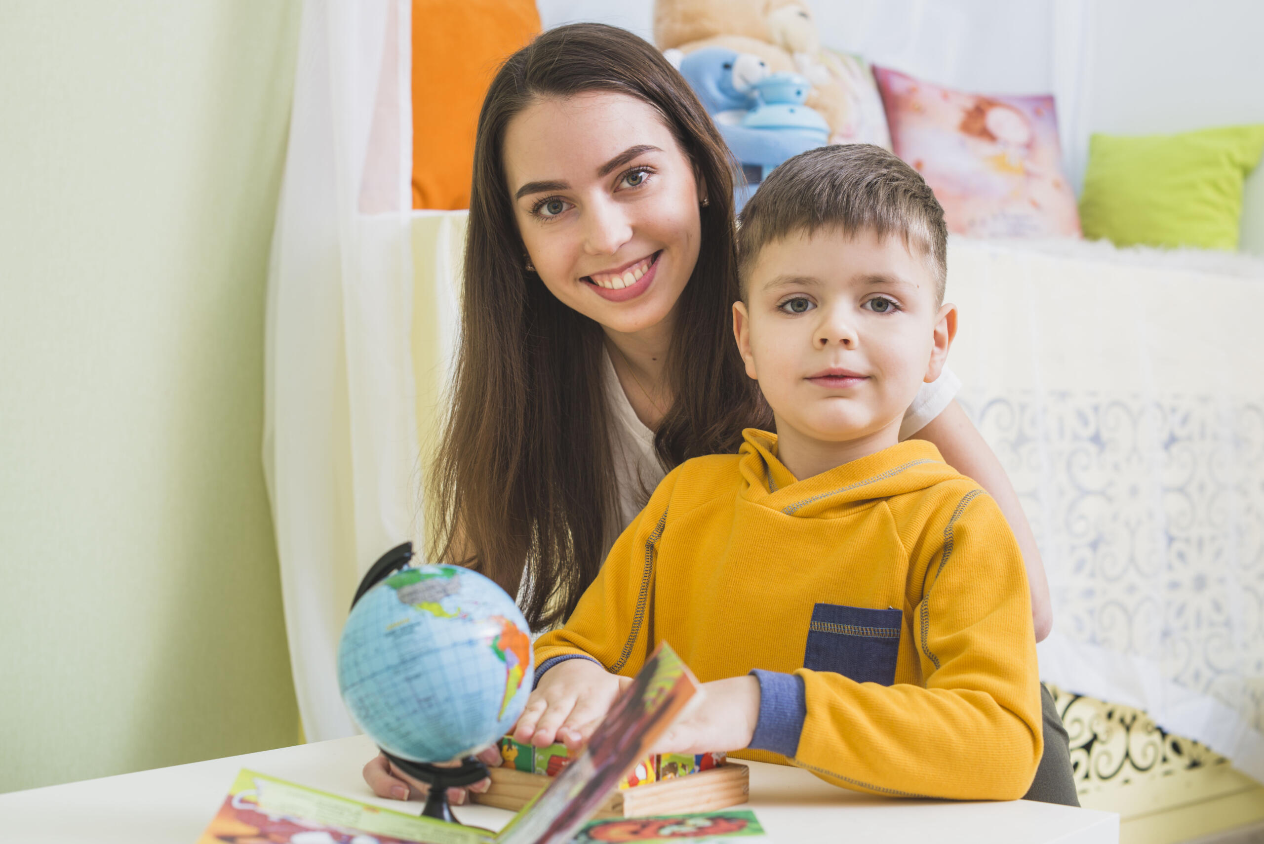 niño sentado junto a su profesora ambos sonrientes mirando a la cámara
