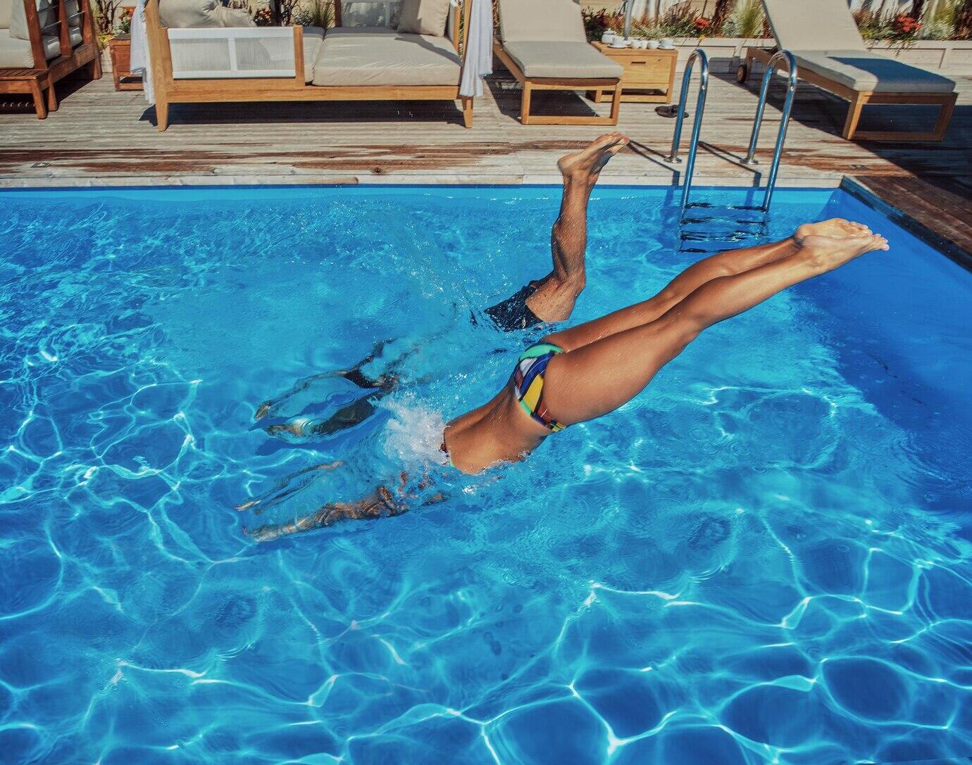 chico y chica lanzándose a la piscina de un clavado