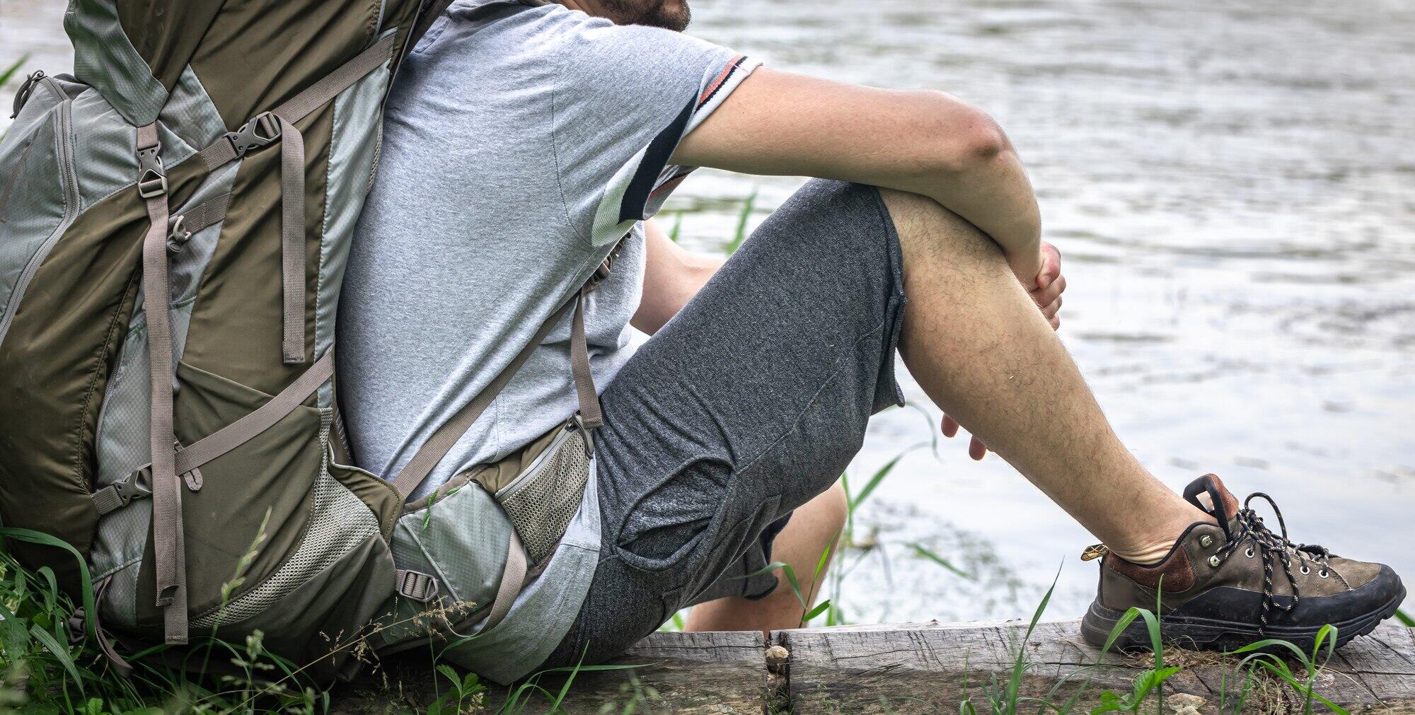 chico con equipo de trekking descansando junto a un lago