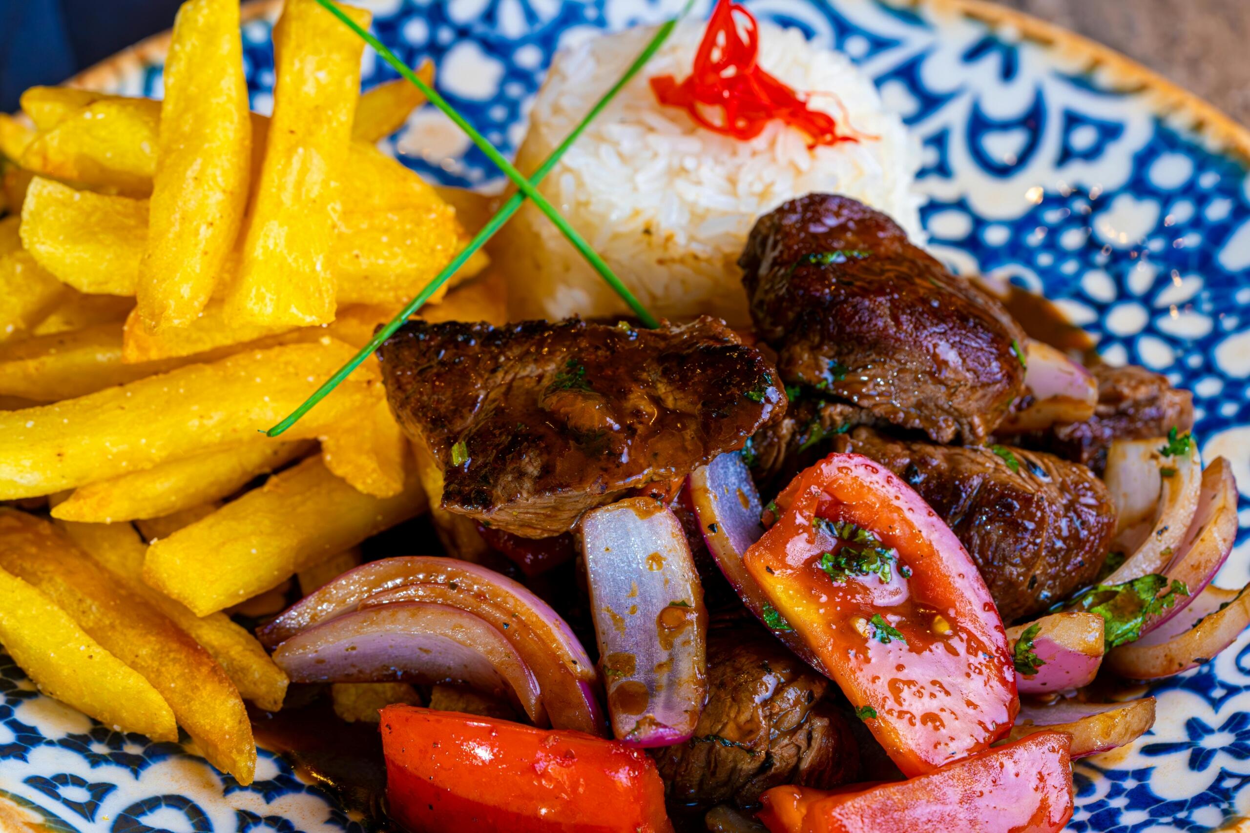 foto en plato detalle de un lomo saltado con papa fritas al lado del lomo y el arroz