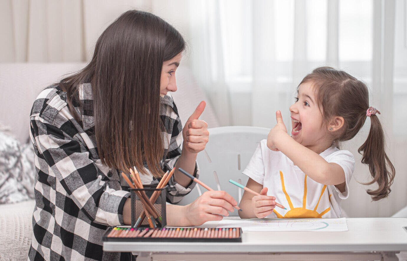 proesora y niña pequeña mirándose sonrientes con el pulgar arriba