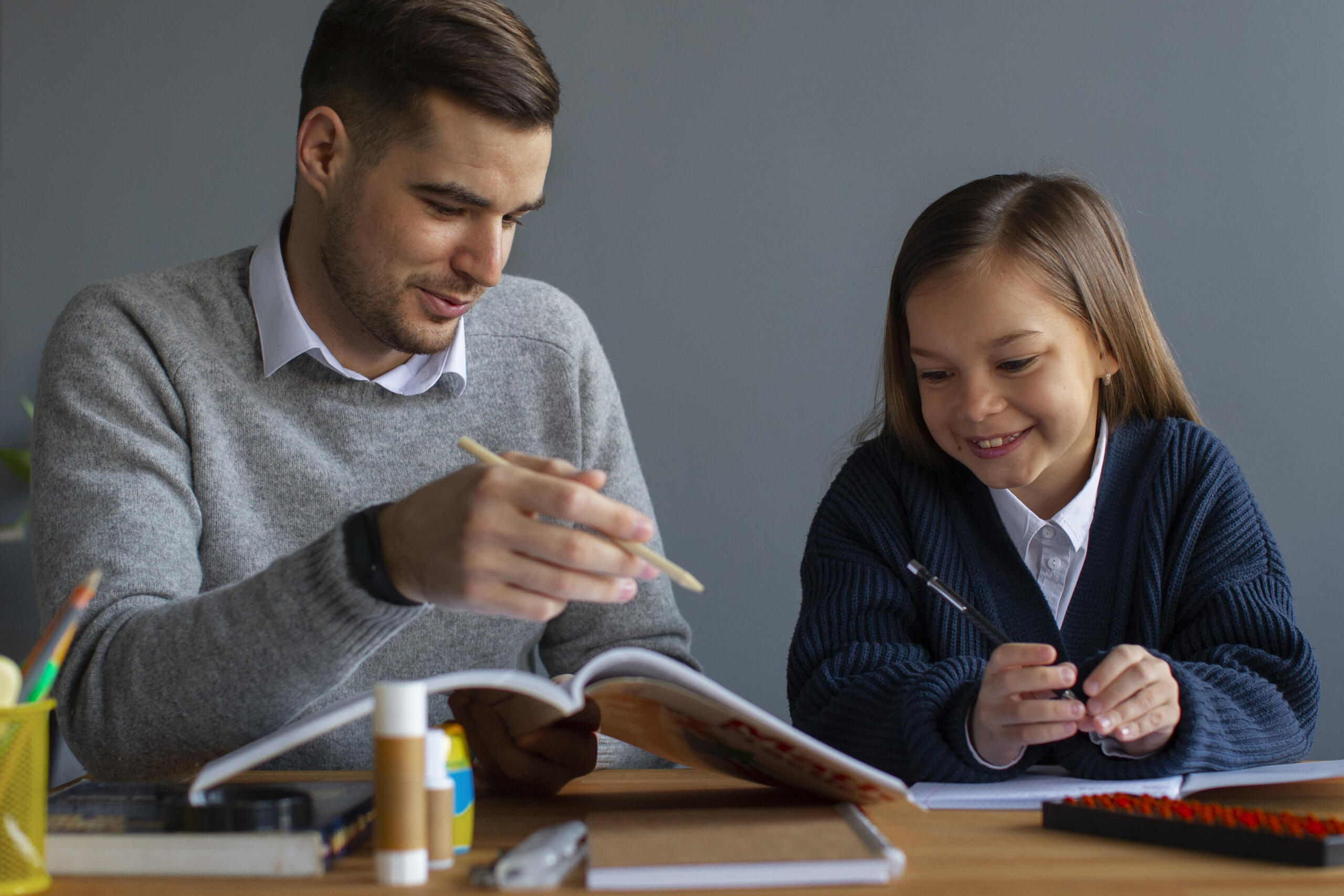 profesor particular explicándole con un libro a una niña sonriente