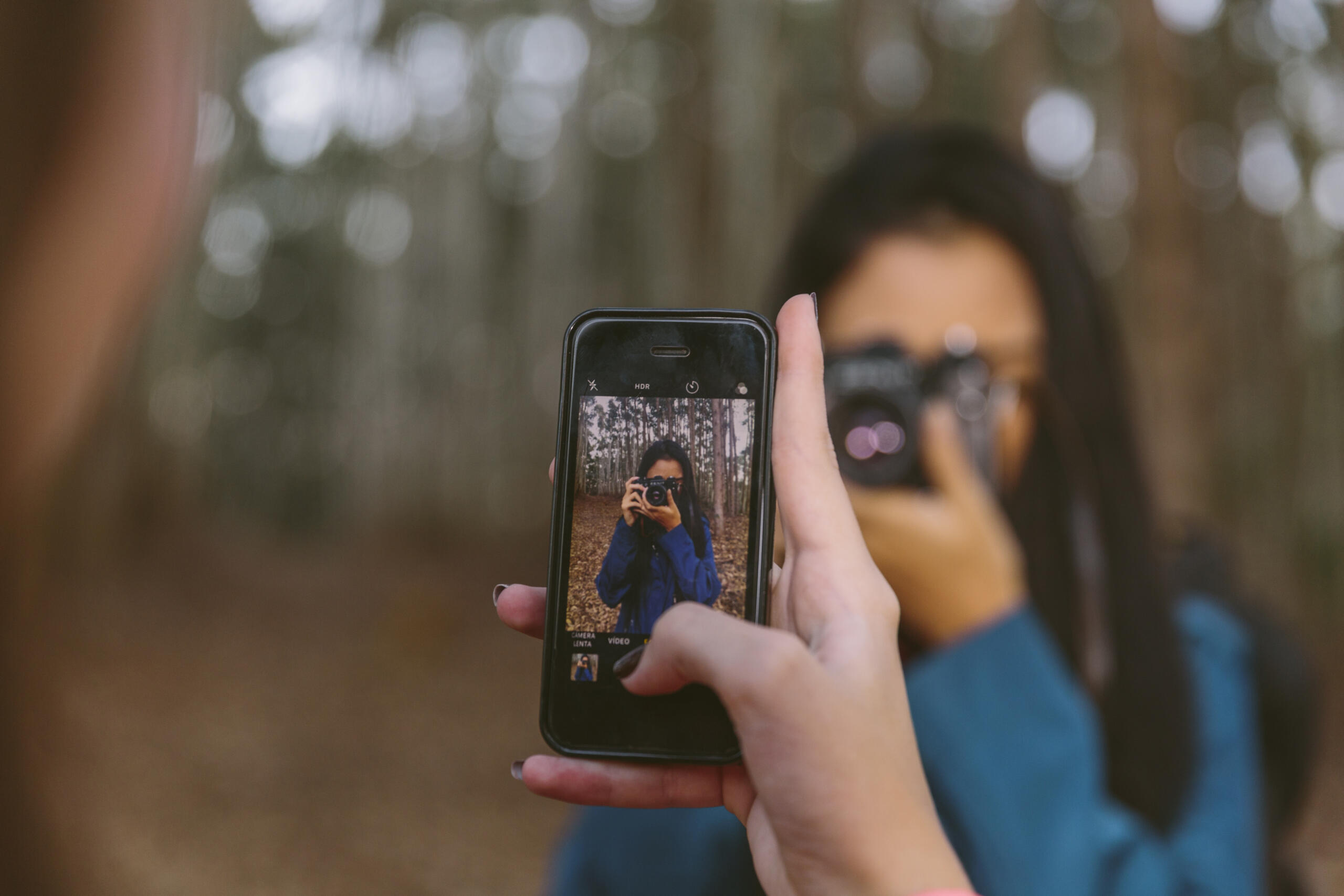 vista de celular tomando una foto a una chica que apunta su camara hacia el celular