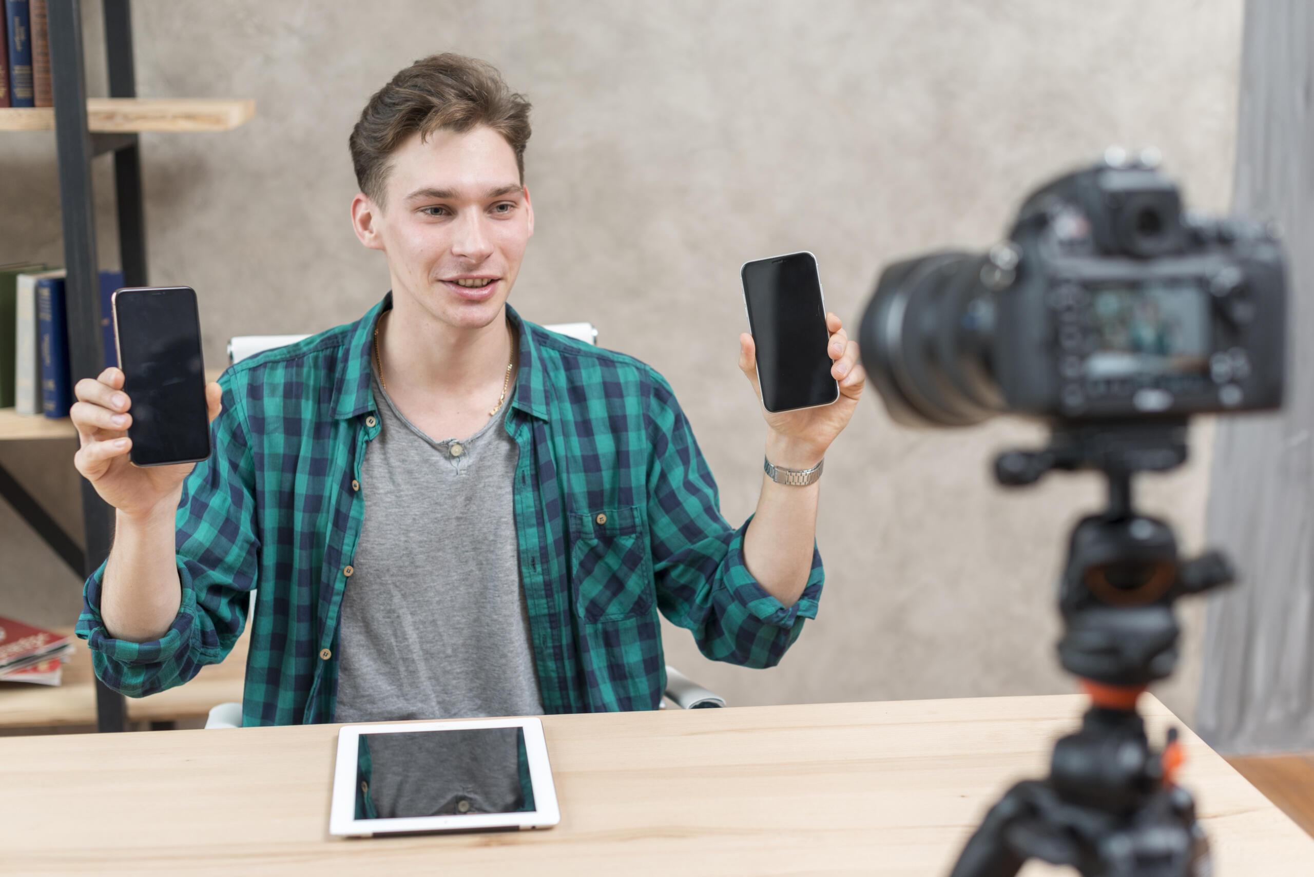 vista de un blogger grabándose mientras compara dos modelos de celular distintos frente a una cámara
