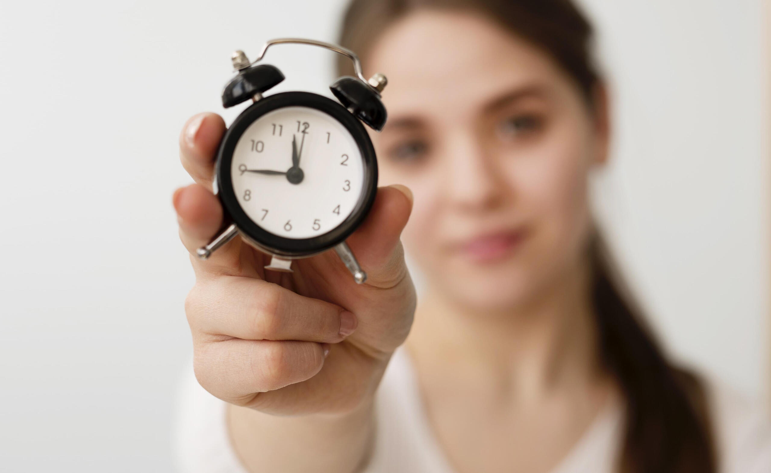 chica sosteniendo un reloj antiguo pequeño frente a la cámara