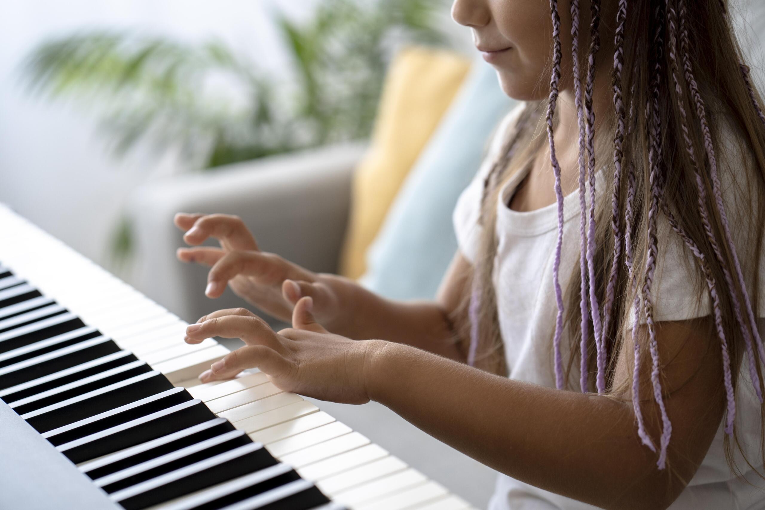 torso de una niña sonriente tocando un teclado electrónico sola