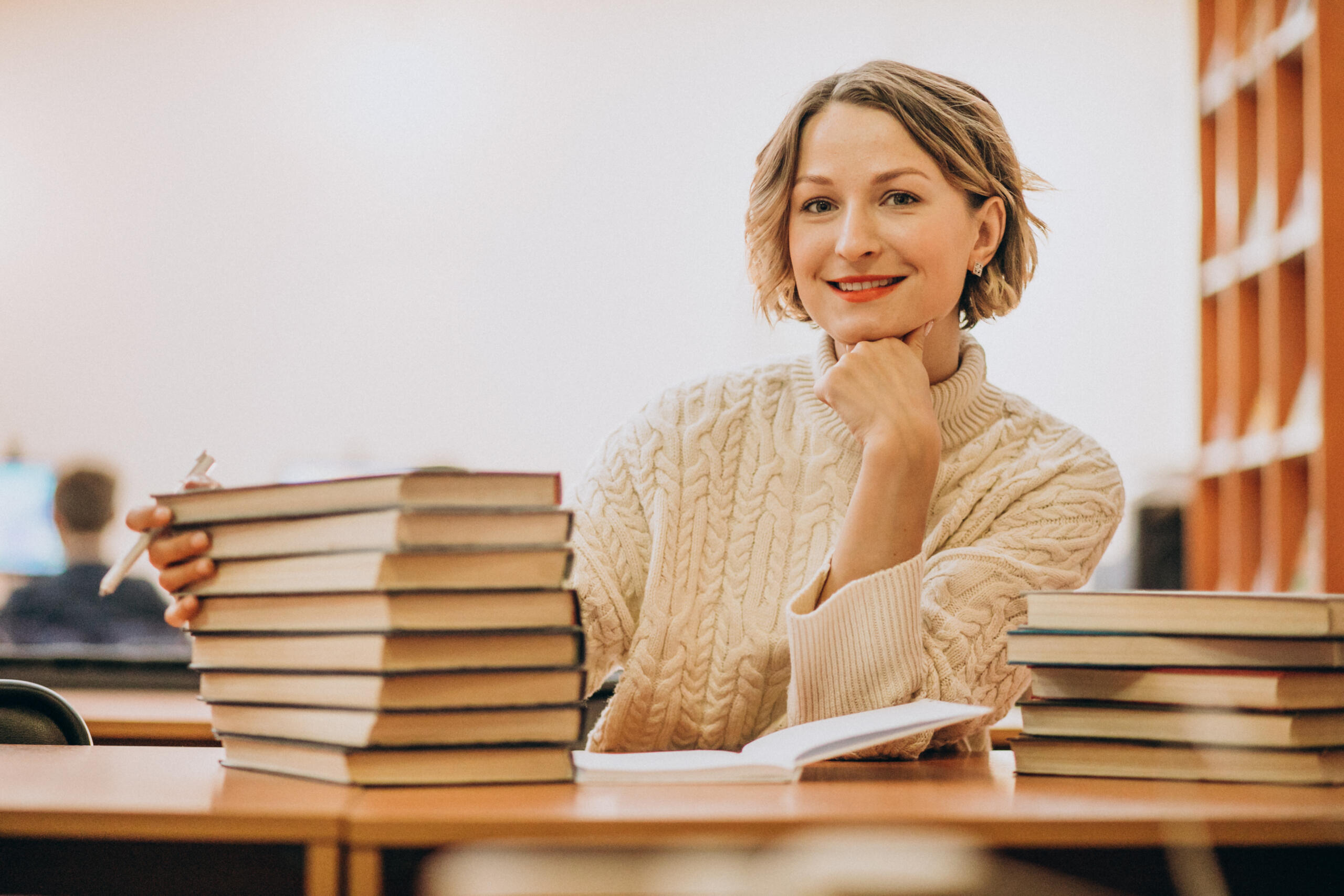mujer con una pila de libros mirando sonriente a la cámara