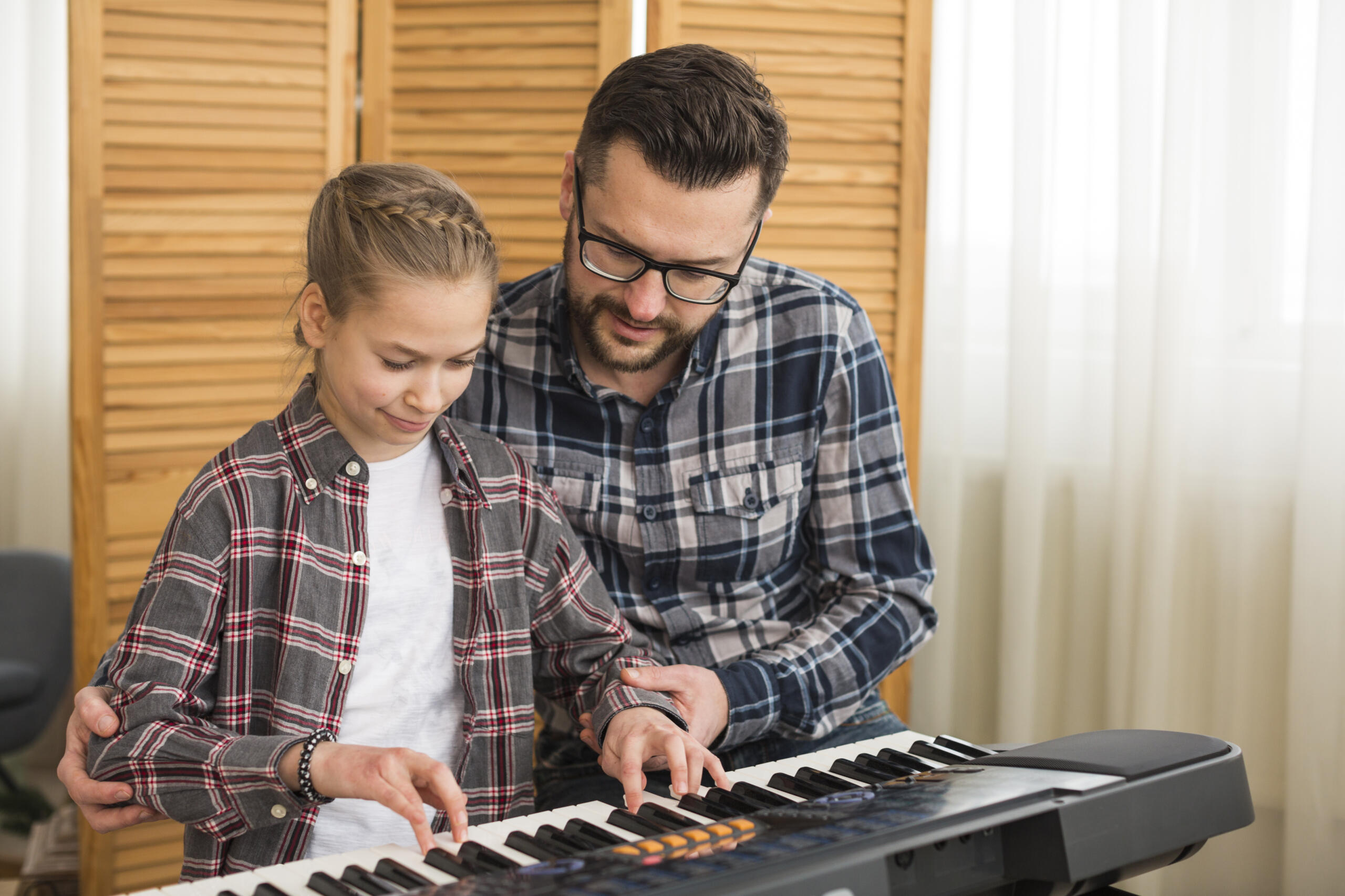 profesor enseñándole a una niña a tocar un teclado electrónico