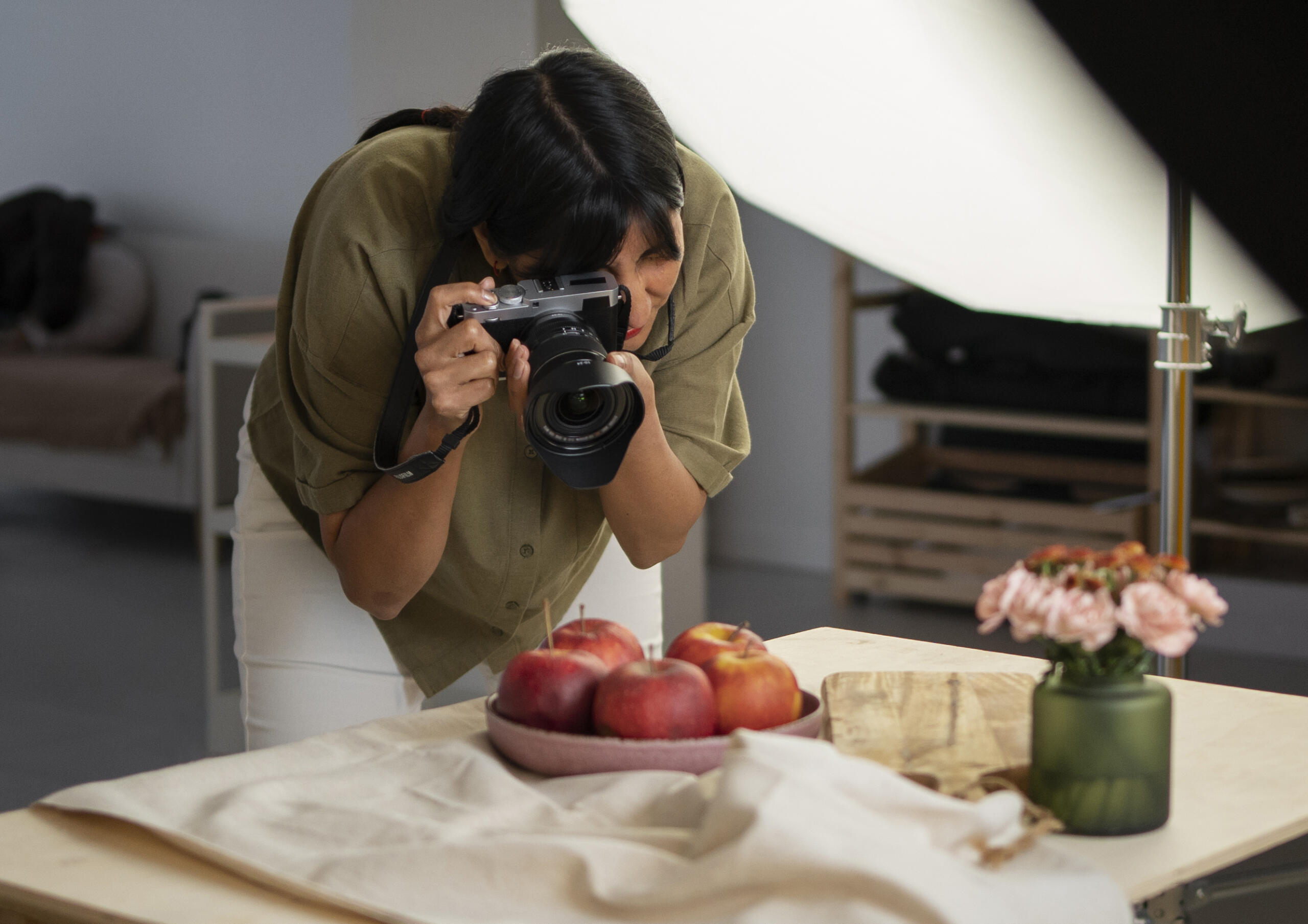 chica con cámara en mano sacando fotografías de un bodegón en estudio