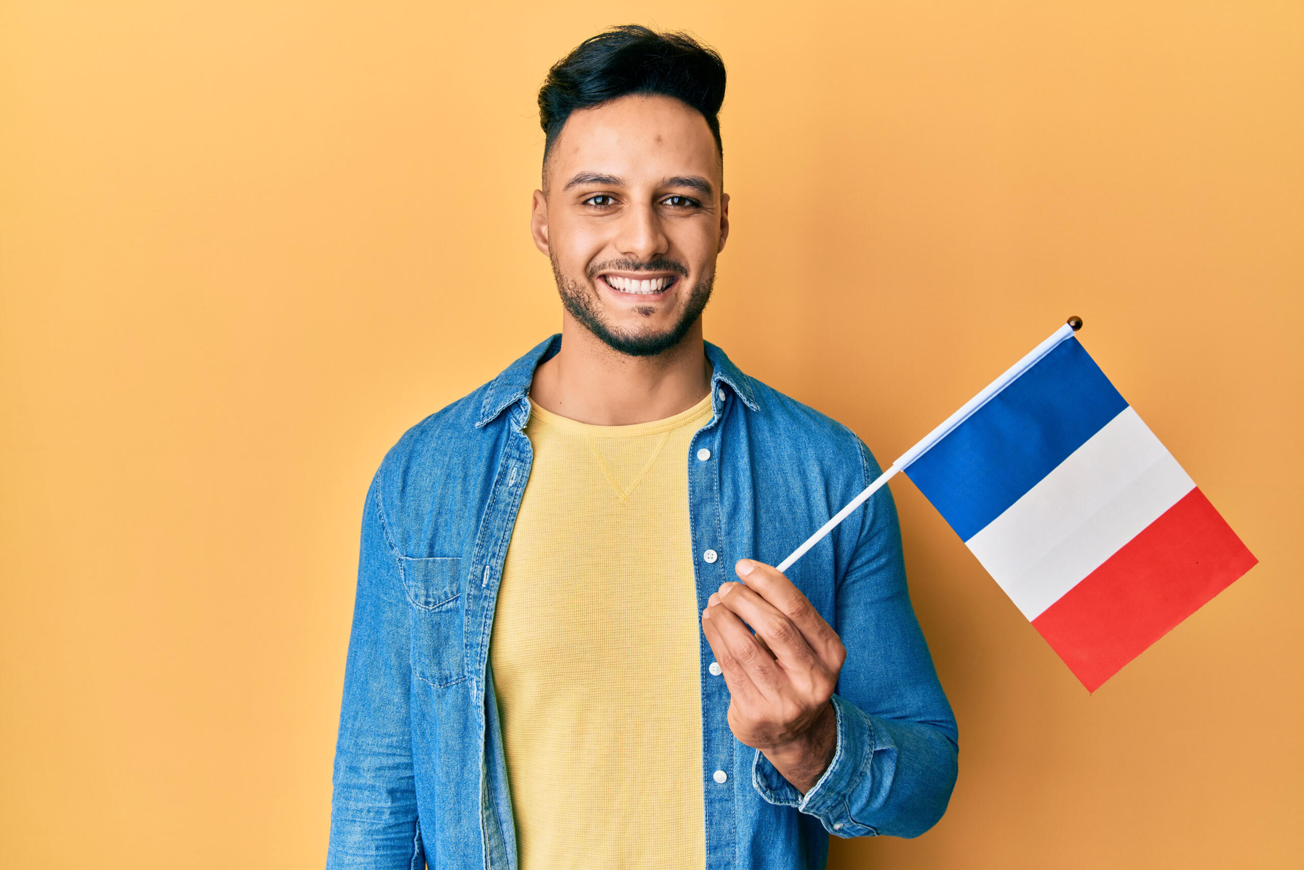 chico sonriente sosteniendo una bandera de francia