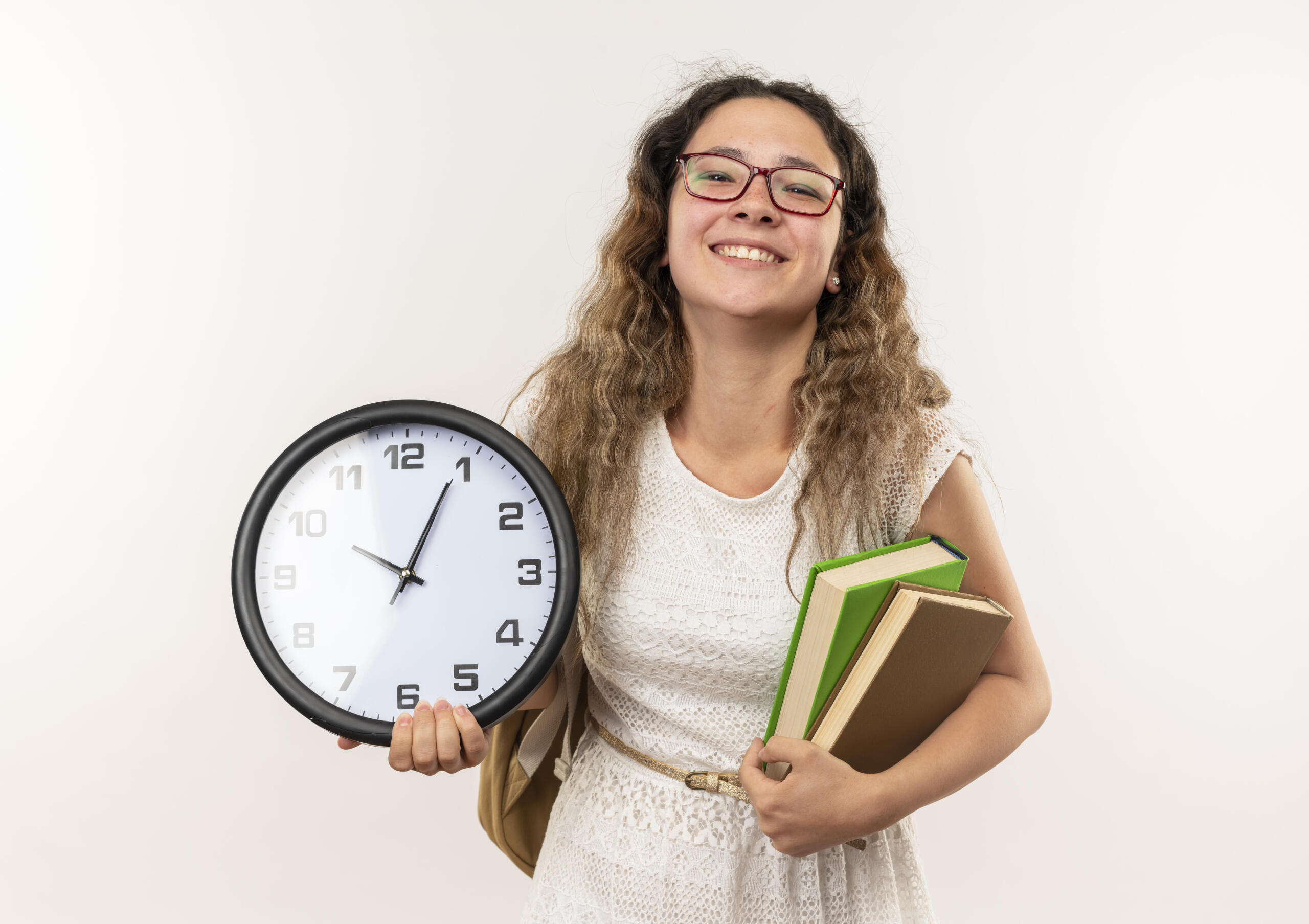 chica sonriente con un reloj gigante y libros entre las manos
