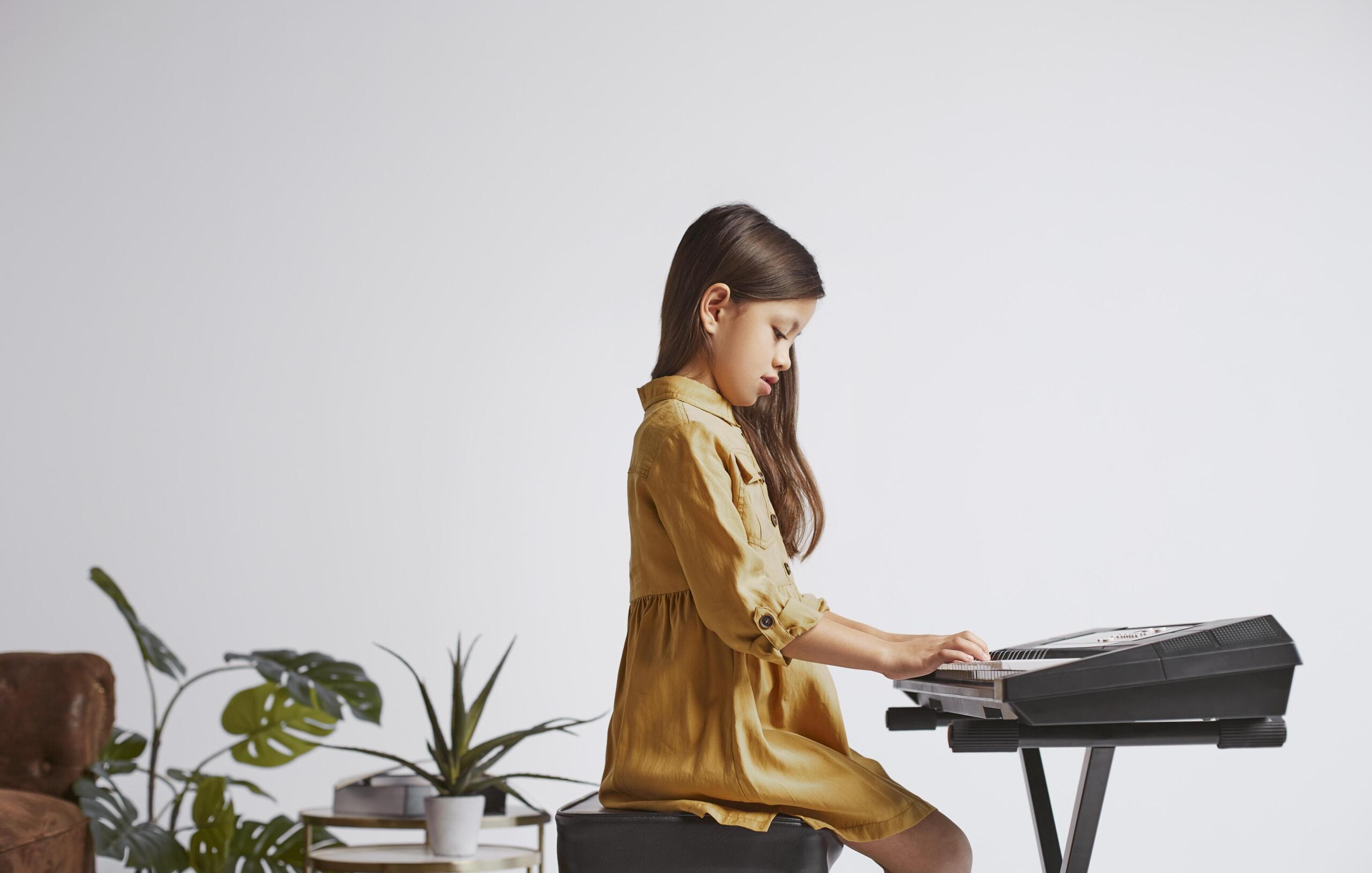 niña sola tocando un teclado electrónico